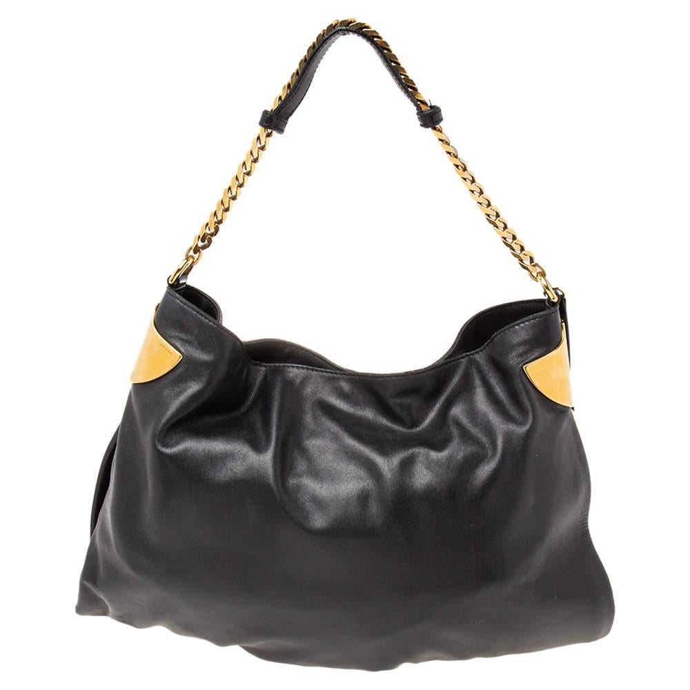 Comfortable to carry without compromising on style, this Gucci 1970 bag is presented in black leather. It features a single chain-link handle with a leather shoulder rest, gold-tone metal detailing on the sides, a dangling tassel charm, and a