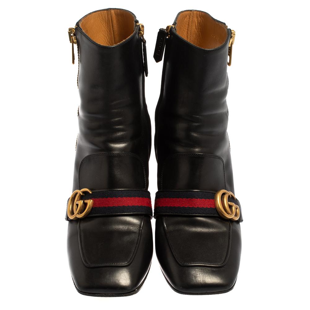 What a wonderful sight! These Gucci boots just bring joy to one's eyes. They are made from black leather and designed with signature web straps carrying the GG logo and block heels embellished with studs and faux pearls. The pair is complete with