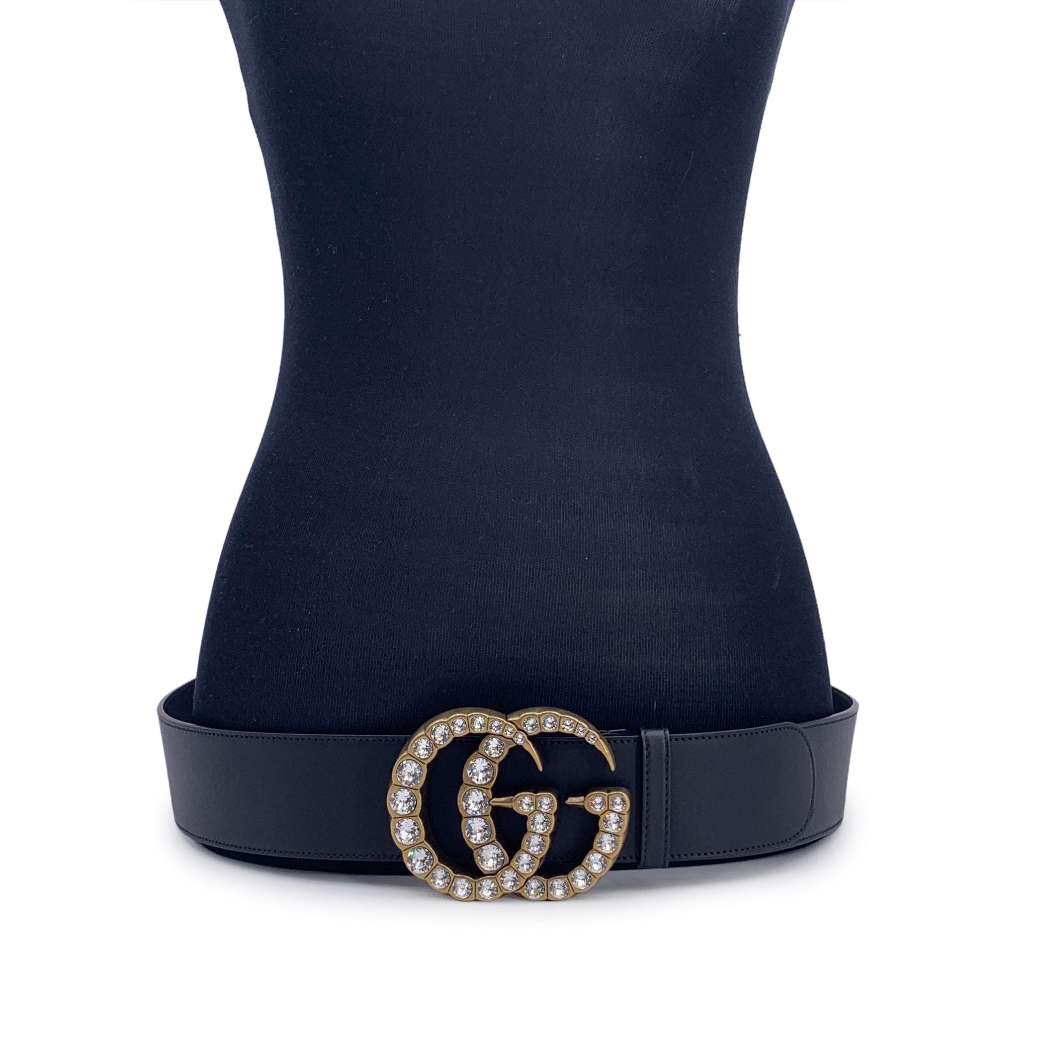 Gucci Marmont wide belt in black leather with GG logo pattern. Big gold metal GG buckle embellished with crystals (3 inches - 7.6 cm tall). Width: 2.6 inches - 6.7 cm. 'GUCCI - Made in Italy' engraved on the reverse of the belt, serial number
