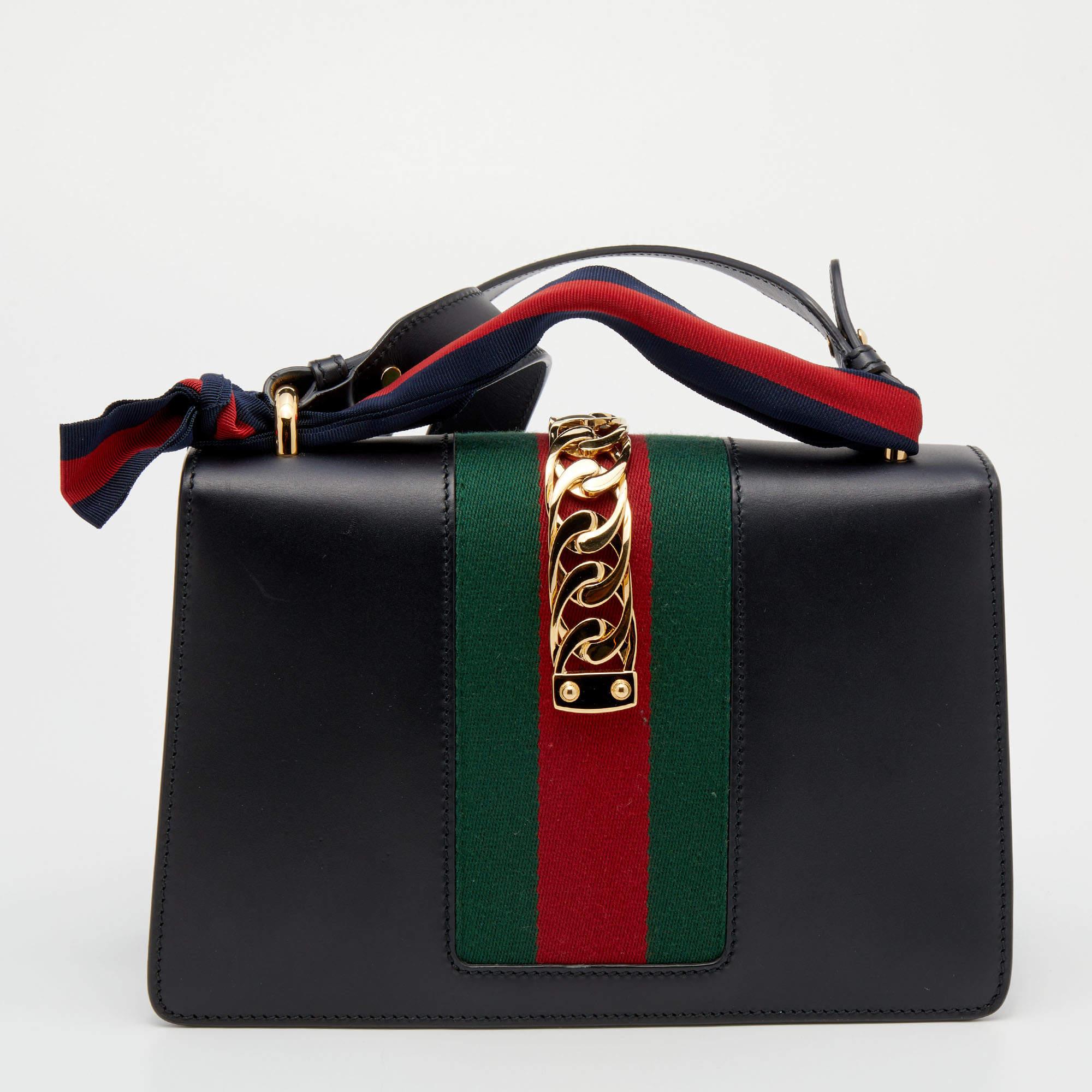 This Sylvie bag from the House of Gucci emerges as an everlasting icon of opulence and elegance with its brilliantly-designed structure. It is crafted from black leather and it has the iconic Web strap with gold-tone chain detailing on the flap.