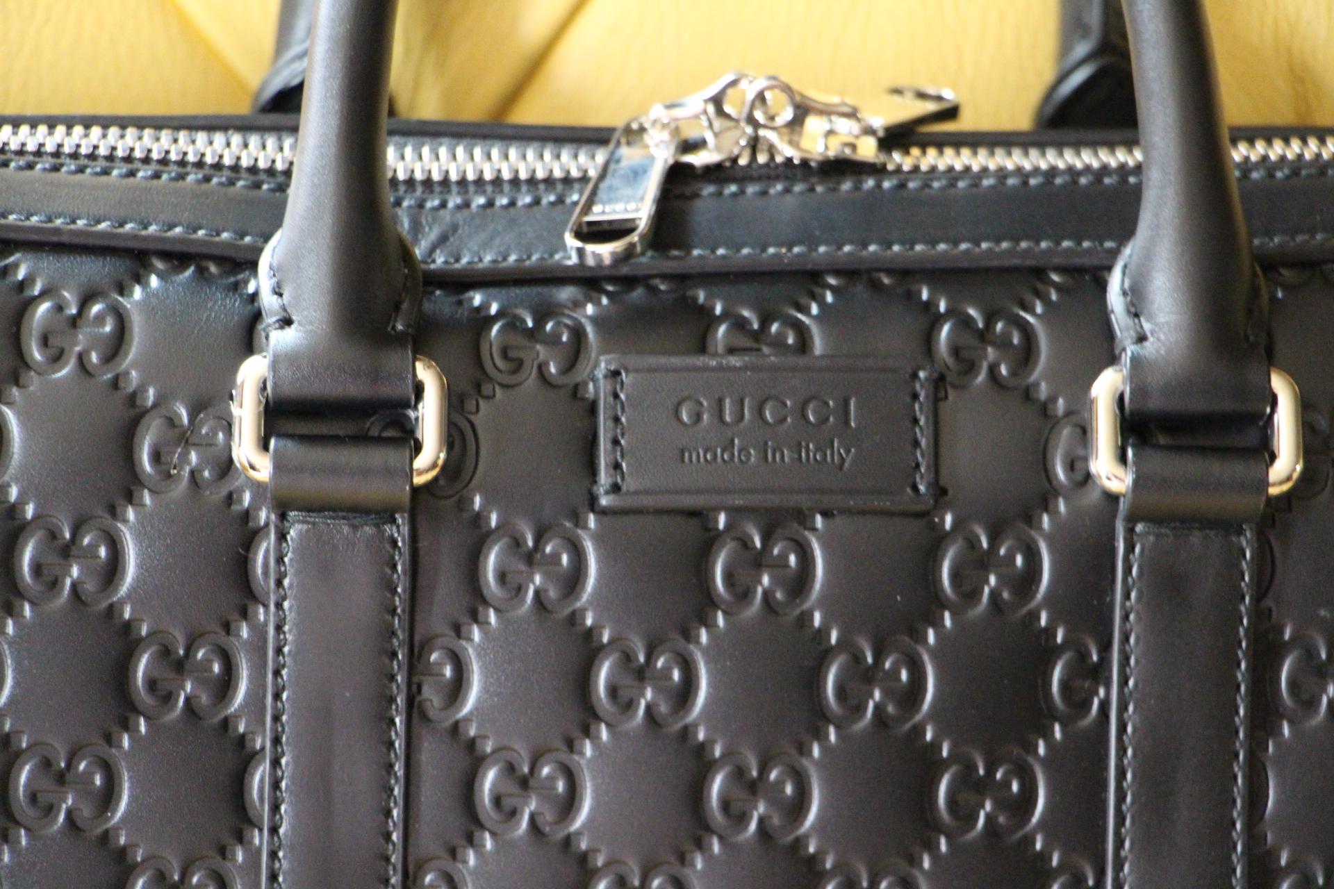 
 Brand new Black Gucci Signature leather bag with black leather trimsand a double zip closure. 
 Palladium-toned hardware
 1 Gucci padlock.
   Interior zipper and smartphone pockets
   Padded iPad compartment
   Double leather handles with 10cm