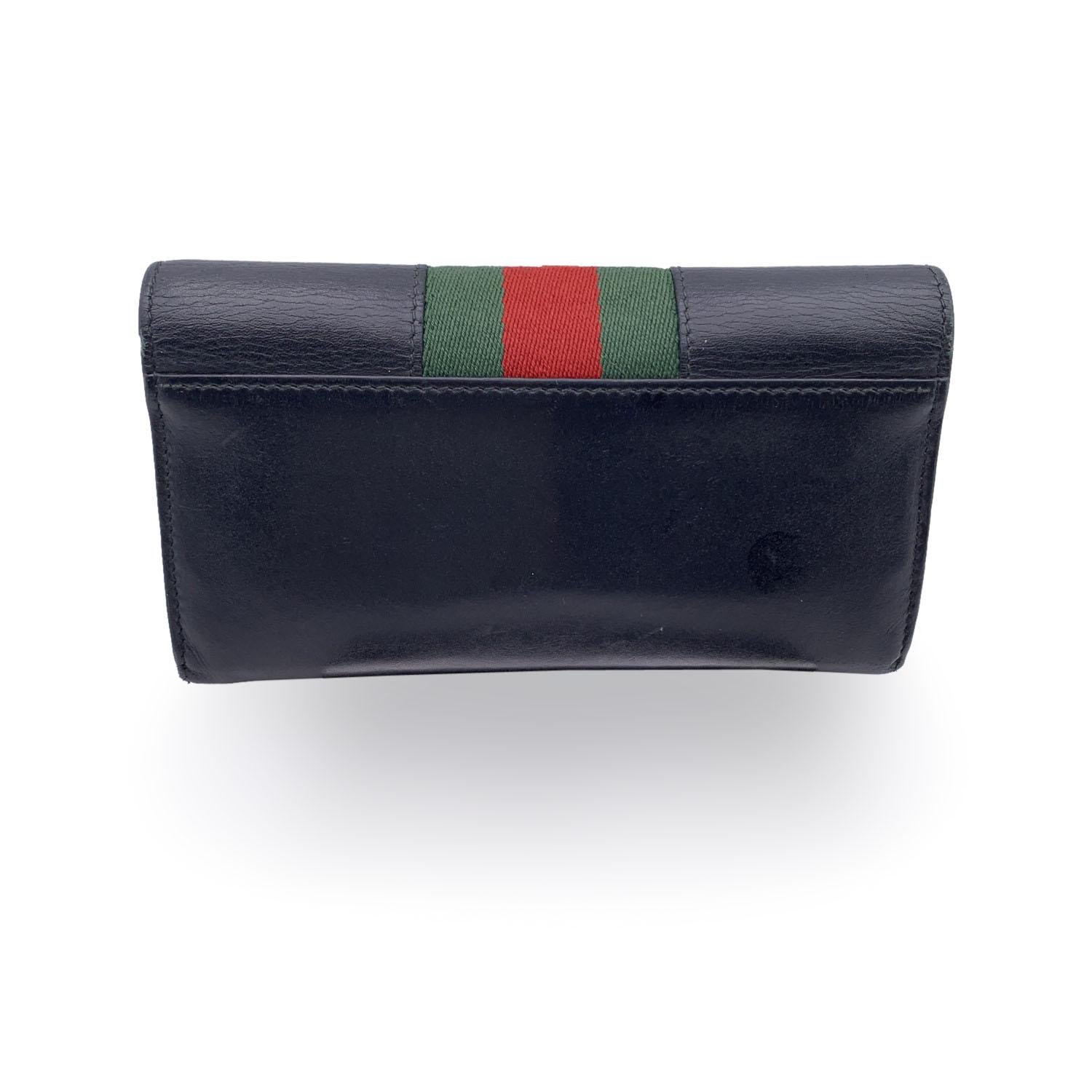 Beautiful Gucci 'Sylvie' Continental Wallet, crafted in black leather with gold metal buckle on the front. Leather interior. Inside it has: 12 credit card slots, 1 zip section for coins, 2 flat open pockets and 2 bill compartment. 'Gucci - Made in