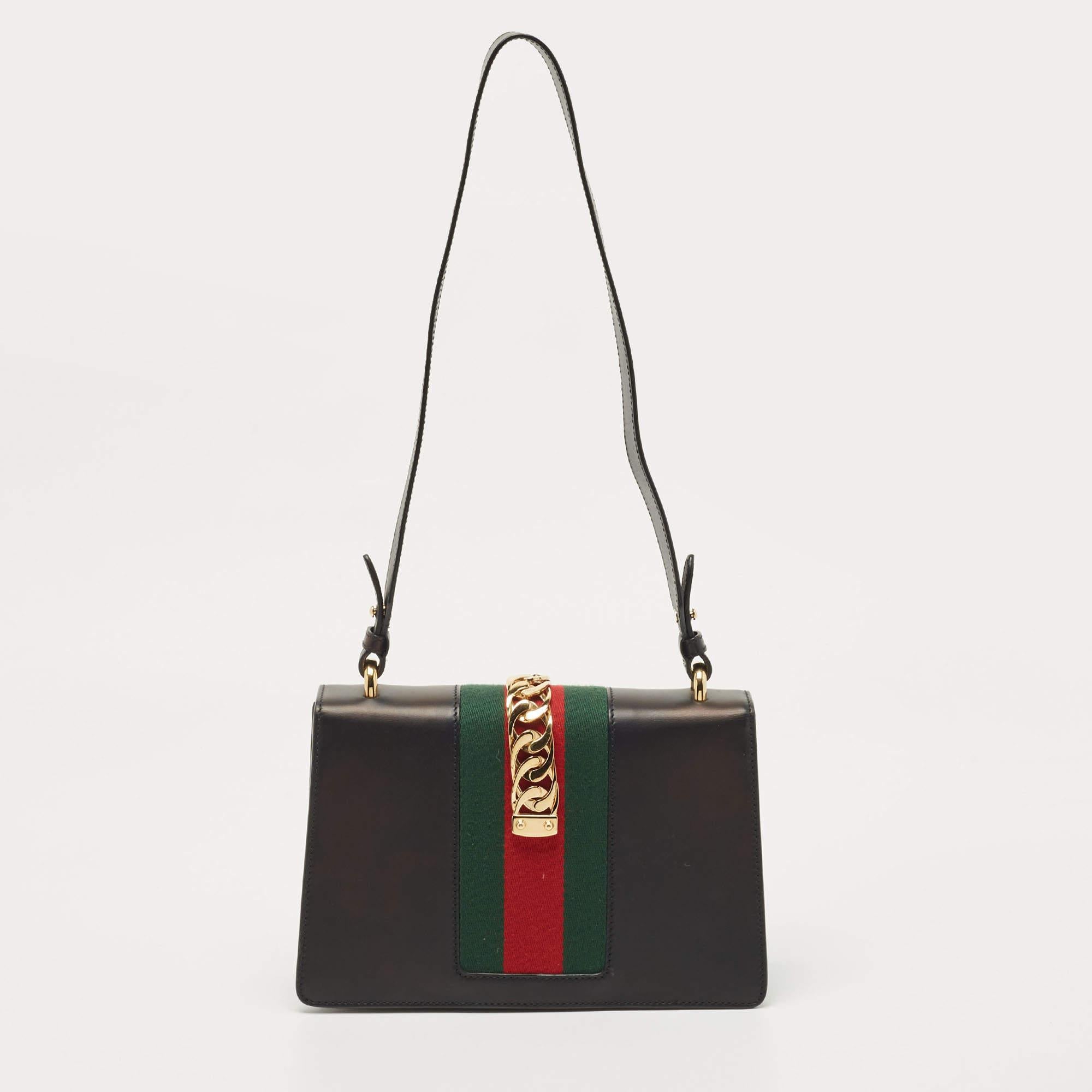 All the creations from Gucci, like this Sylvie bag, reflect a sense of innovation and tradition. Crafted from leather, it is admired for its timeless elegance and structured silhouette. The striking chain design on the Web stripe detailing elevates