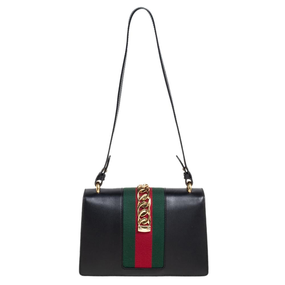 From the house of Gucci comes this gorgeous Sylvie shoulder bag that will perfectly complement all your outfits. It has been luxuriously crafted from black leather and styled with a chain-web decorated flap and a buckle lock to secure the Alcantara