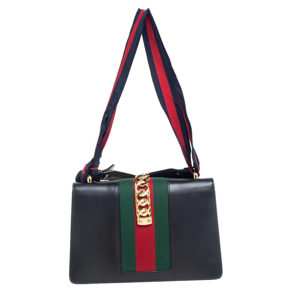 From the house of Gucci comes this gorgeous Sylvie shoulder bag that will perfectly complement all your outfits. It has been luxuriously crafted from black leather and styled with a chain-Web decorated flap and a buckle lock to secure the Alcantara