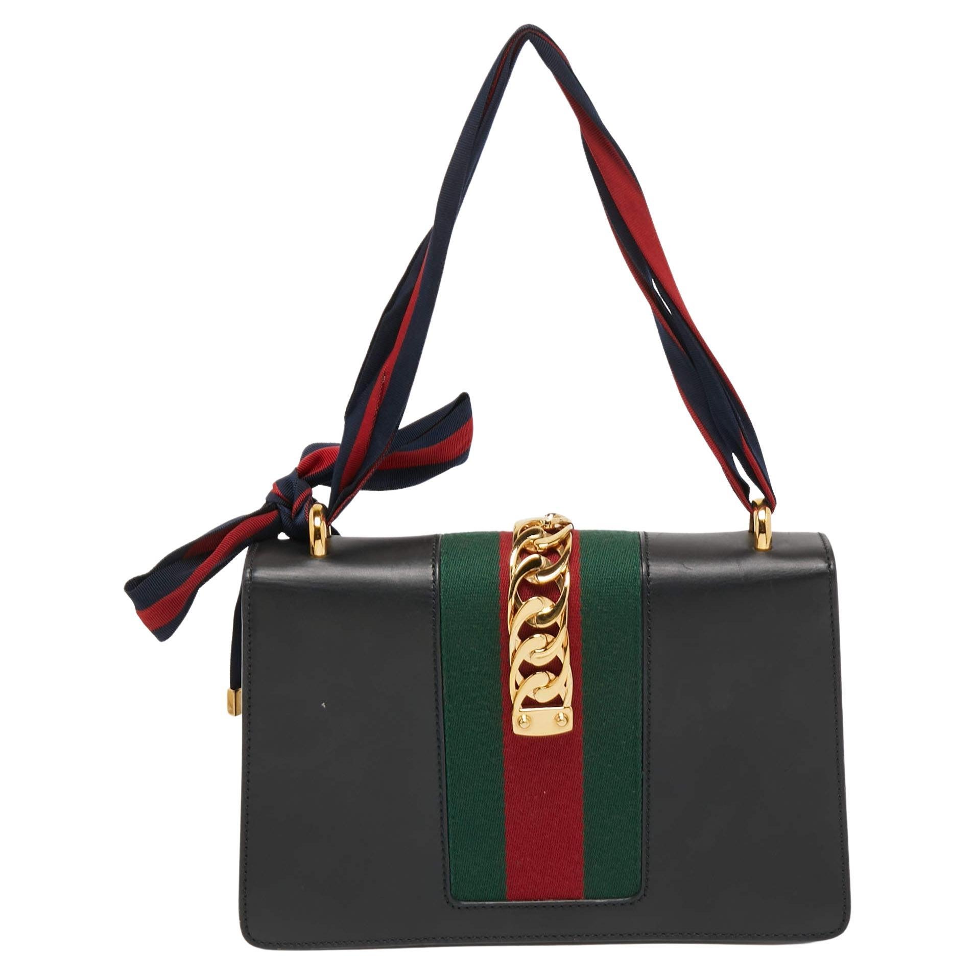 Gucci's Sylvie bag brings House codes and high-grade materials in a contemporary design. This version is crafted using black leather and styled with the chain-Web decorated flap and a buckle lock to secure the Alcantara interior. The bag is complete