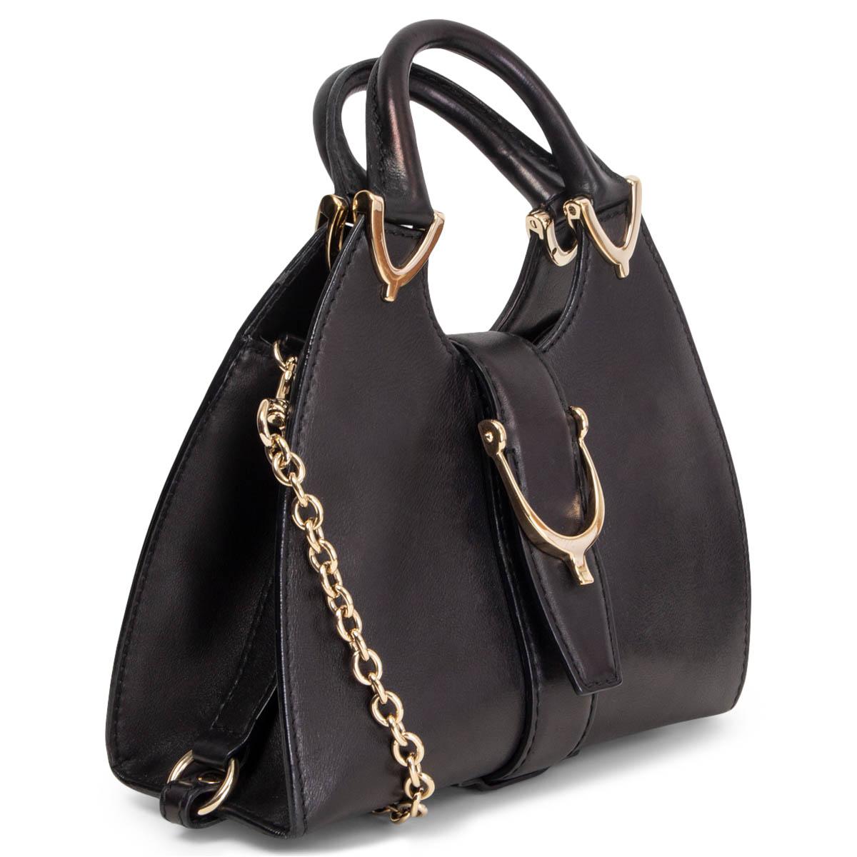 100% authentic Gucci Stirrup small top handle shoulder bag is crafted of black polished smooth calfskin leather. The bag features looping rolled leather top handles with light gold-tone brass stirrup style links and a cross over strap with a stirrup
