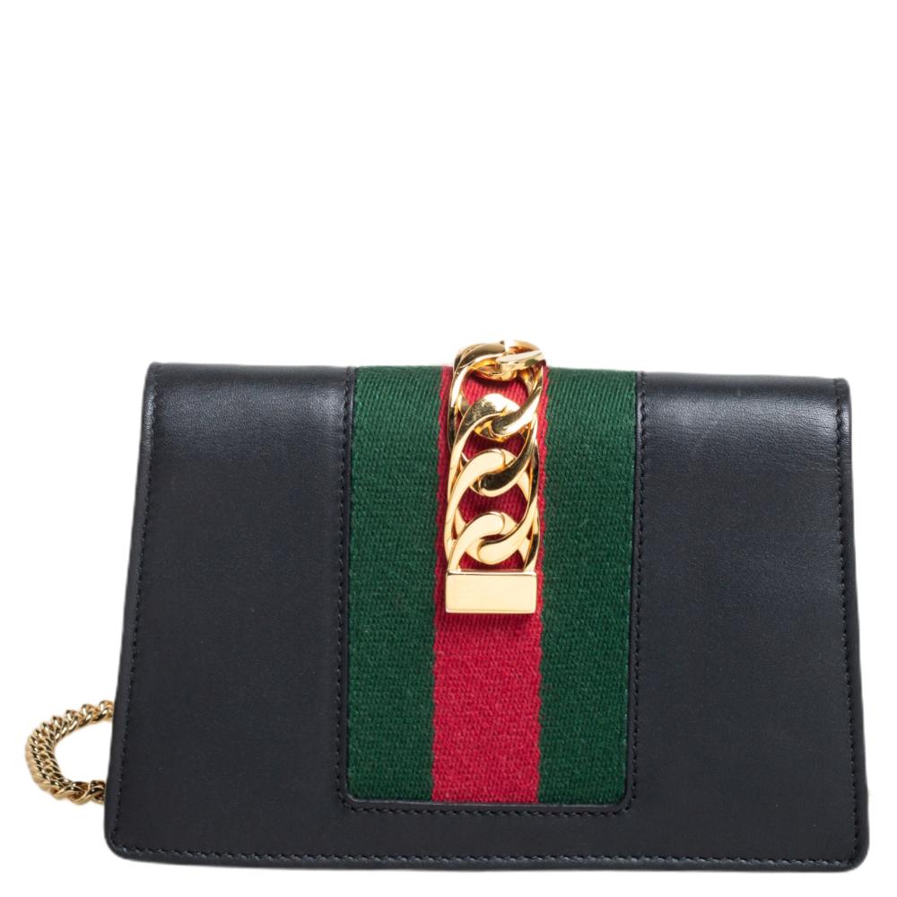 From the house of Gucci comes this gorgeous Sylvie crossbody bag that will perfectly complement all your outfits.
 It has been luxuriously crafted from black leather and styled with a chain-web decorated flap and a buckle lock to secure the suede
