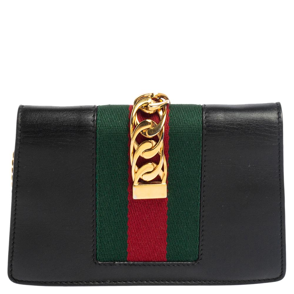 From the house of Gucci comes this gorgeous Sylvie wallet-on-chain that will perfectly complement all your outfits. It has been luxuriously crafted from black leather and styled with a chain-web decorated flap and a buckle lock to secure the suede