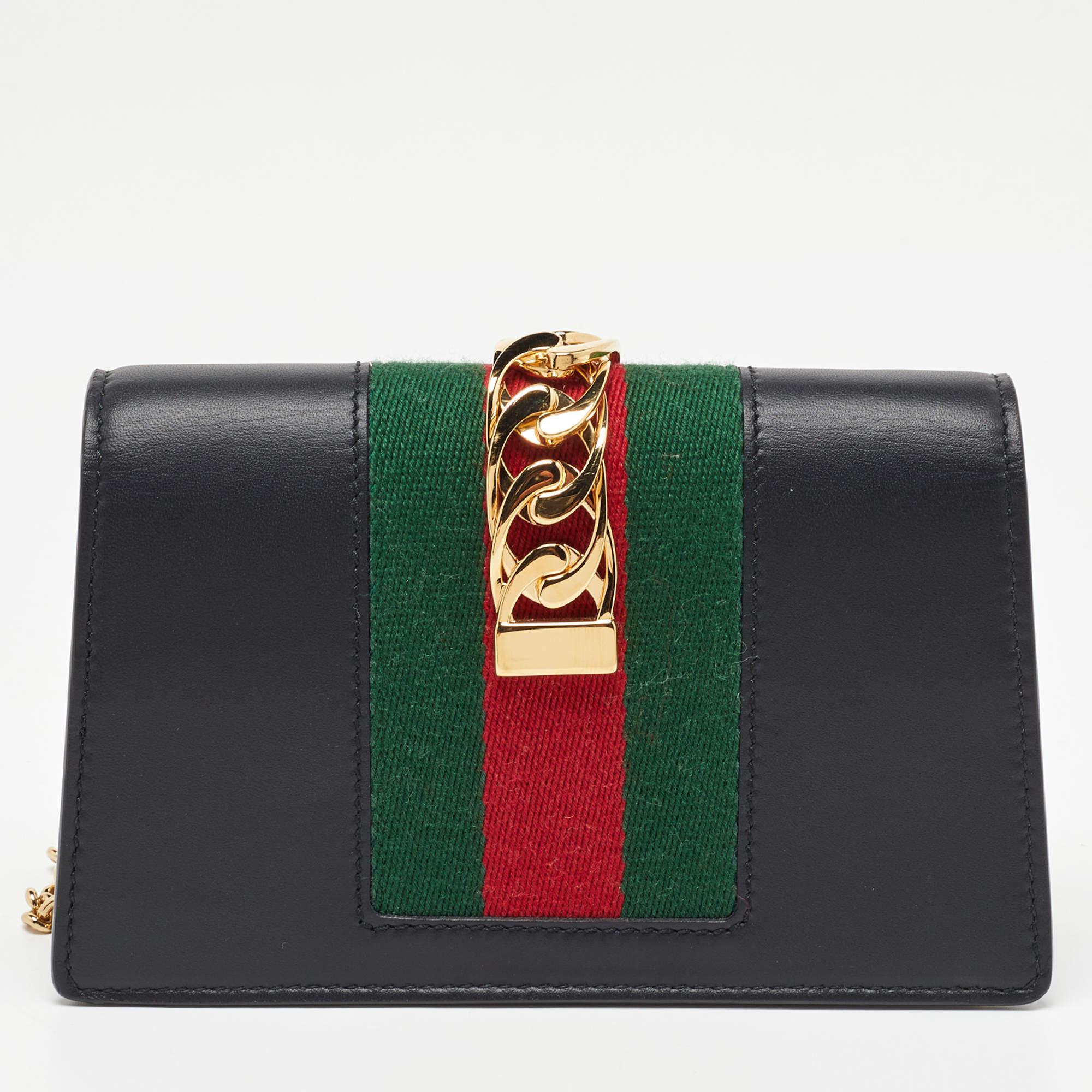From the house of Gucci comes this gorgeous Sylvie WOC that will perfectly complement all your outfits. It has been luxuriously crafted from black leather and styled with a chain-web decorated flap and a buckle lock to secure the suede interior. The