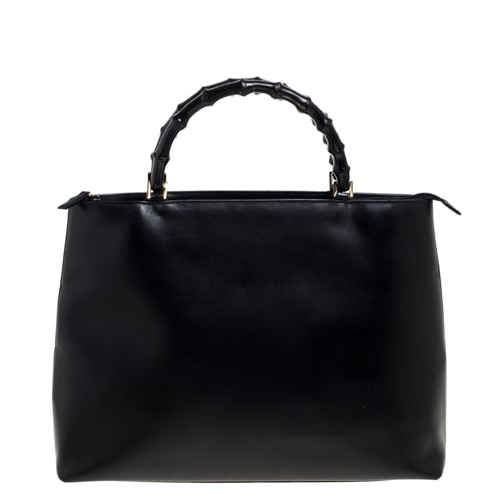 This Gucci tote is sure to keep you fashion-forward. Designed out of black leather, this bag comes with two bamboo handles. It comes with protective metal base studs in gold-tone hardware. The interior of this Italian-made piece is spacious to carry