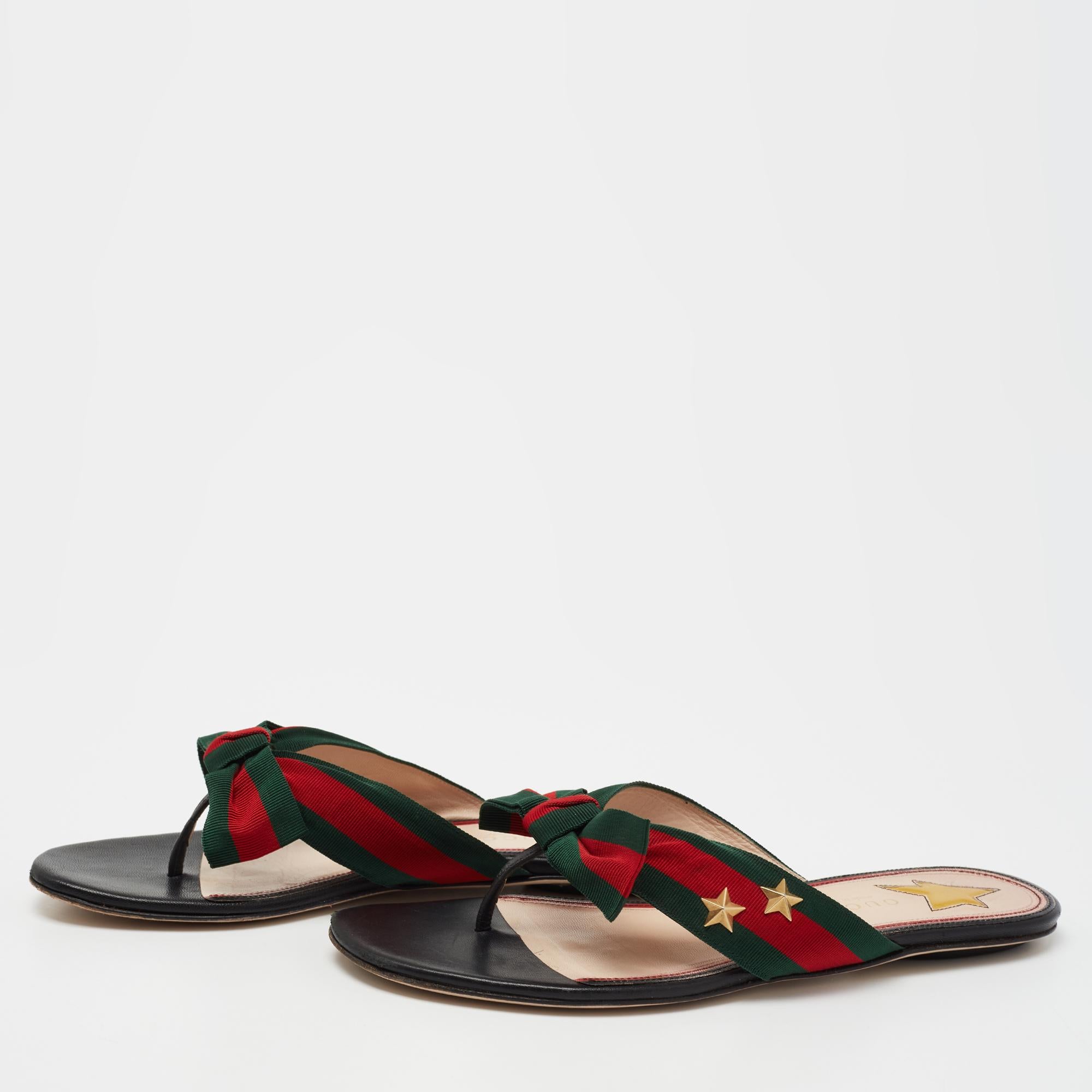 Lend your feet with complete comfort and luxury in these thong flats from the House of Gucci. They are fashioned from black leather, which is embellished with a Web stripe and bow accent on the upper. These thong sandals are completed with