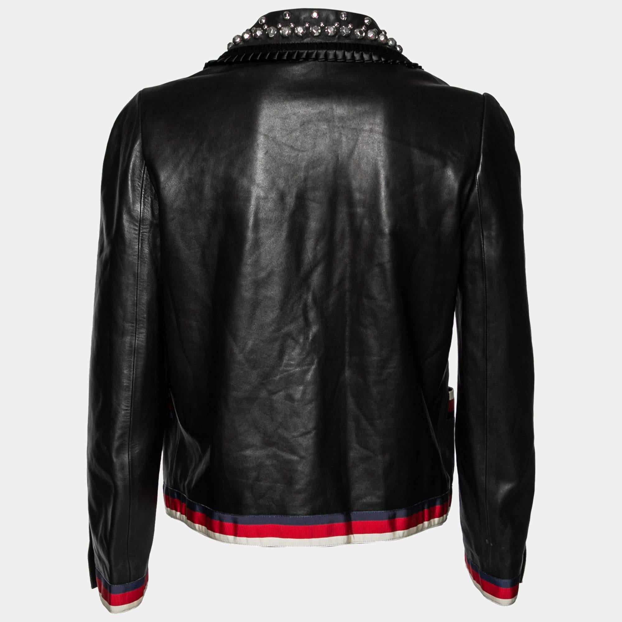 Gucci's statement choice of signature elements and classy design makes each of their creation worth owning. This jacket is truly a stunning piece! It is fashioned in black leather and accented with Web stripe trims. It has a studded collar, a bow