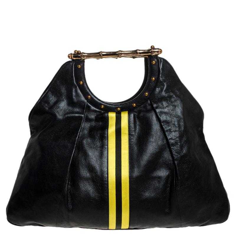 This Gucci handbag will instantly elevate your outfits. Crafted in Italy, it is made from leather and comes in a classic shade of black. This tote is held by lovely bamboo handles, features small stud detailing, two yellow stripes in the middle, a
