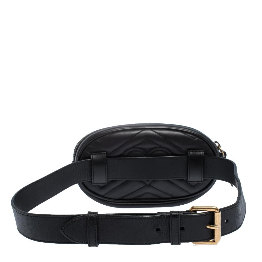 The Gucci Marmont bag has been exquisitely crafted from black leather featuring the signature Matelasse pattern all over and is equipped with a suede interior. On the front, there is the GG logo in gold-tone metal and the leather belt is provided