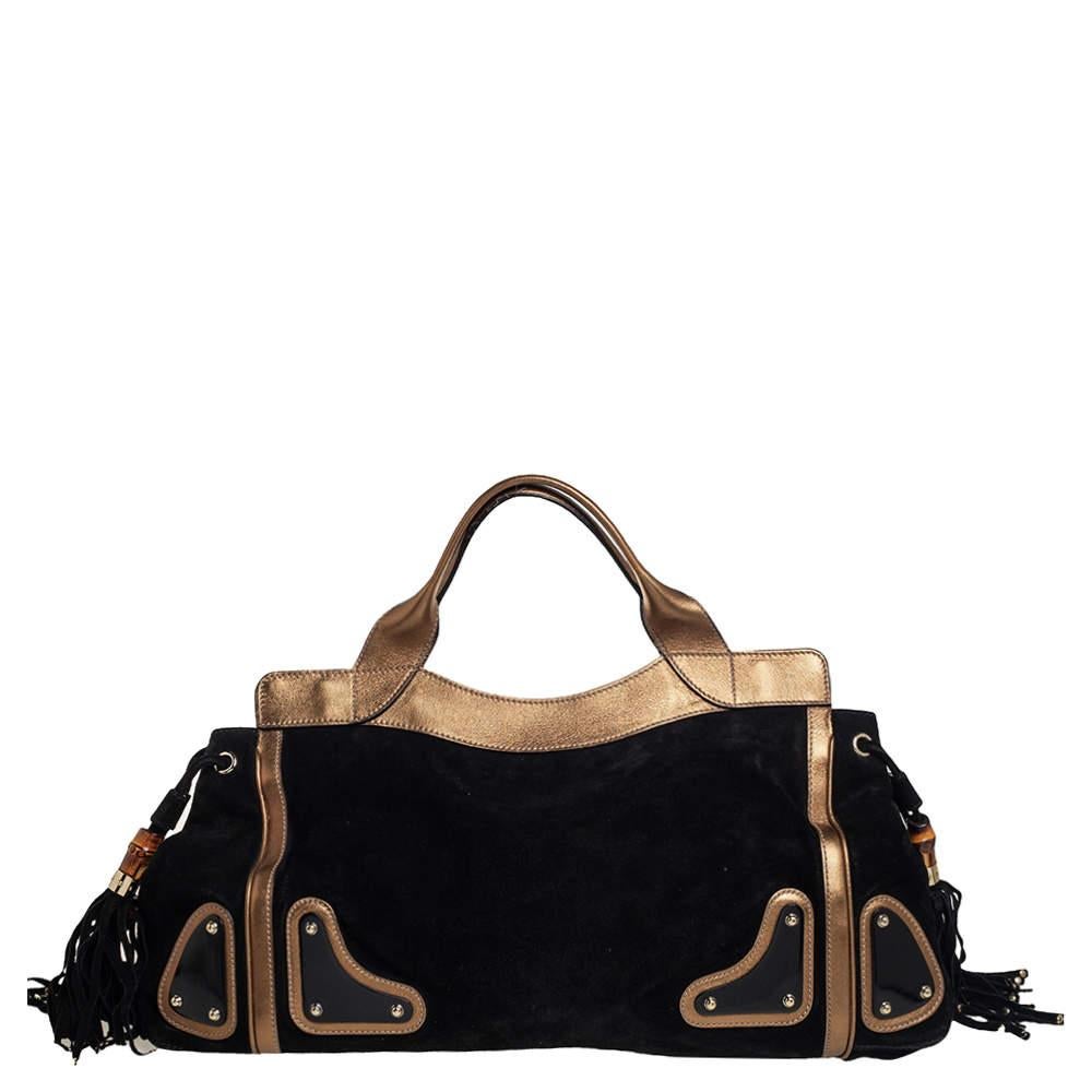 An essential wardrobe accessory, this Gucci handbag is surely a must-have. Incorporate a touch of glamour into your clothing with this inviting suede & leather handbag. It has black & metallic gold hues, logo detailing in the front, dual handles,