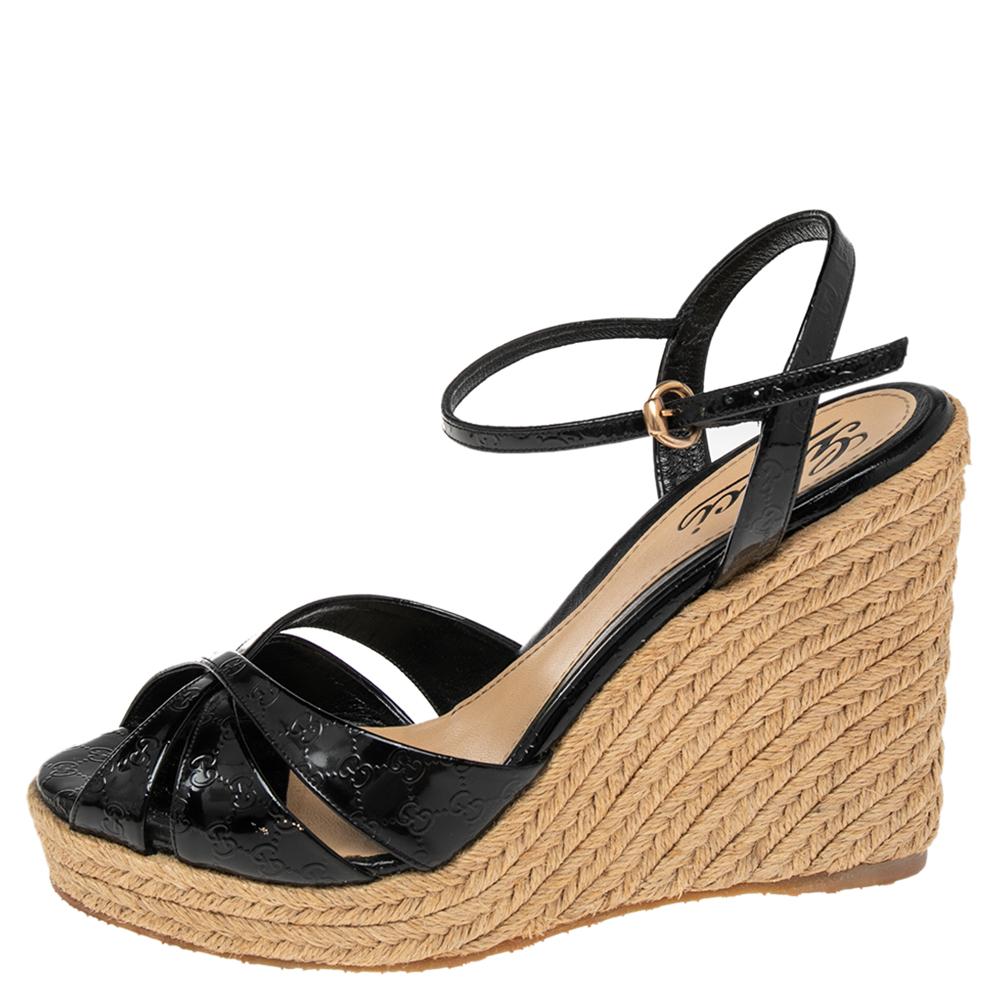 Penelope espadrilles from the house of Gucci is designed in gorgeous black Microguccissima patent leather. It is set on a braided jute wedge heel and secured with an ankle strap buckle closure. We think it makes a perfect pair to flowy skirts and
