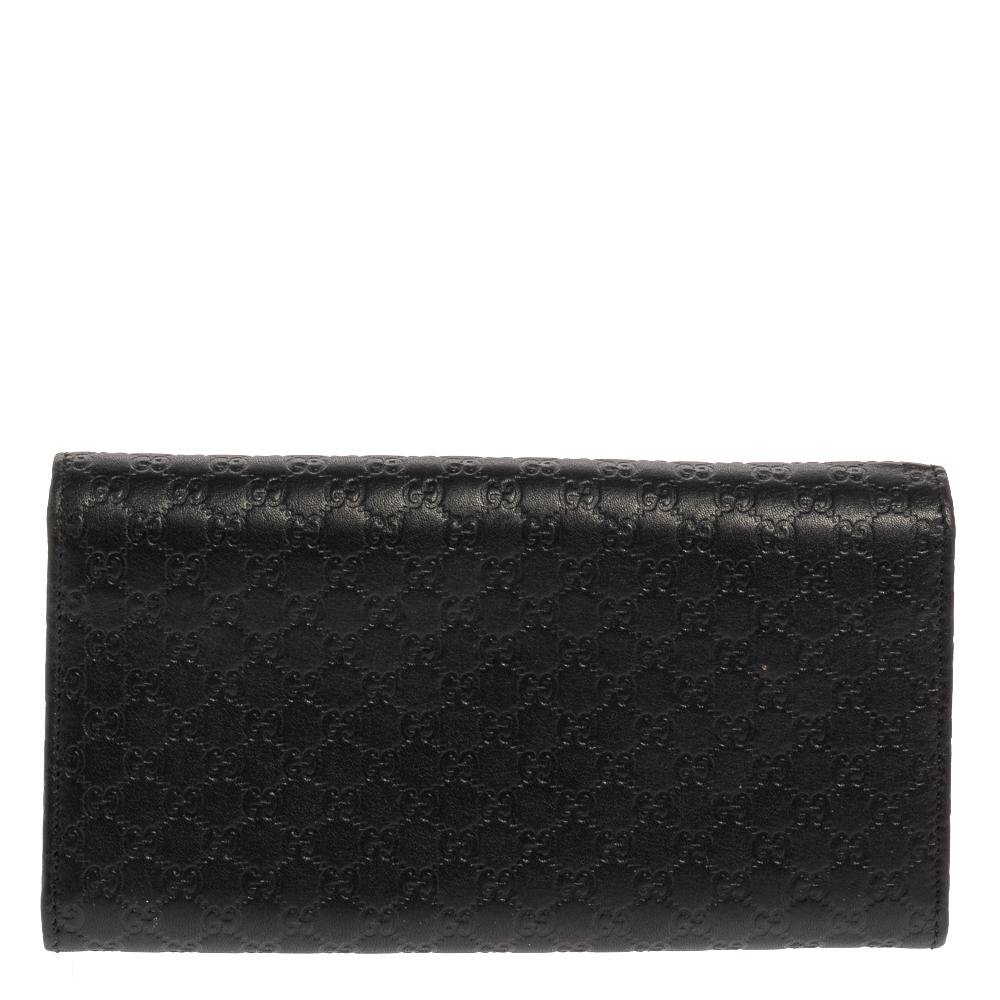 Made from the signature Microguccissima leather in black, this continental wallet from Gucci is beautified with a bow on the front flap. The flap opens to a sleek interior featuring multiple compartments and card slots. This wallet comes with a