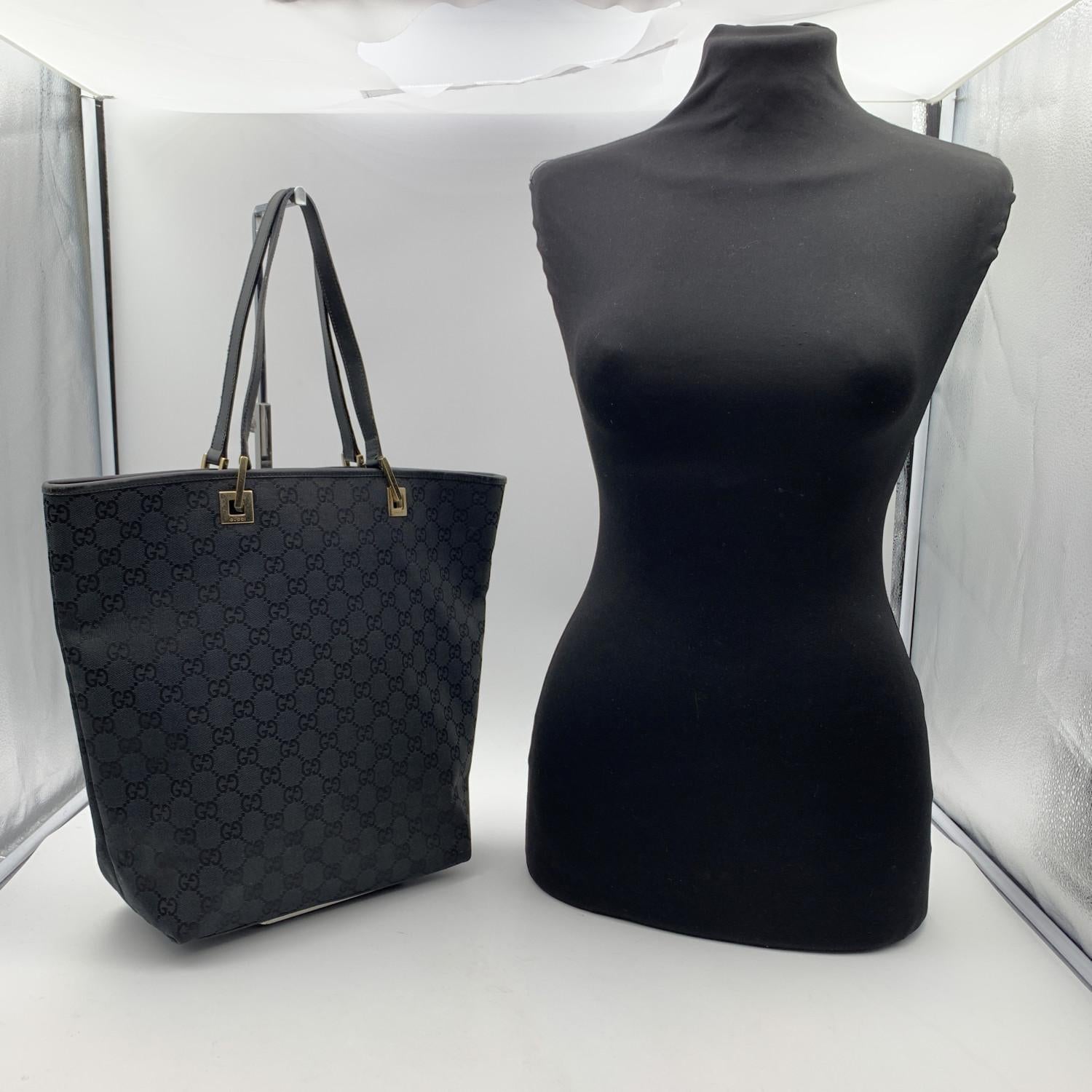 Gucci tote crafted in black monogram canvas with black genuine leather trim and shoulder strap. Signed light gold metal hardware. Open top. Inside, black fabric lining. 1 side zip pocket inside. 'GUCCI - made in Italy' tag inside (with serial number