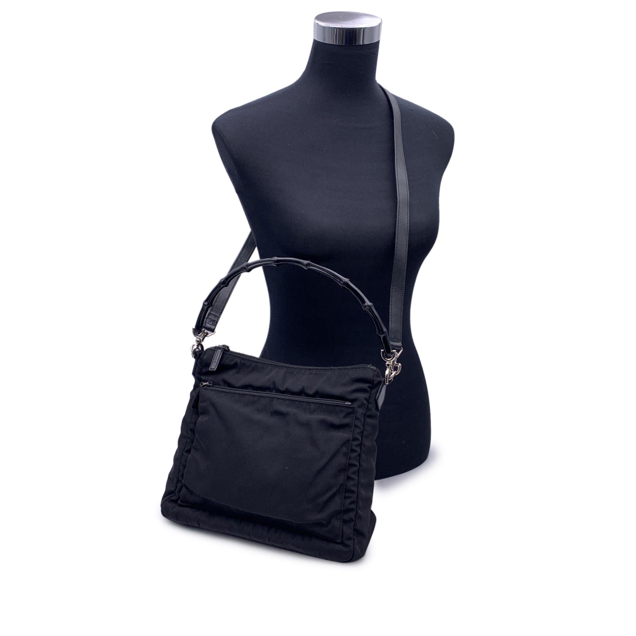 Beautiful Gucci 2Way shoulder bag, crafted in black nylon canvas with black leather trim. Black bamboo handle and removable shoulder strap. 1 front zip pocket. Upper zipper closure. Silver metal hardware. Black lining with 1 side zip pocket. 'Gucci