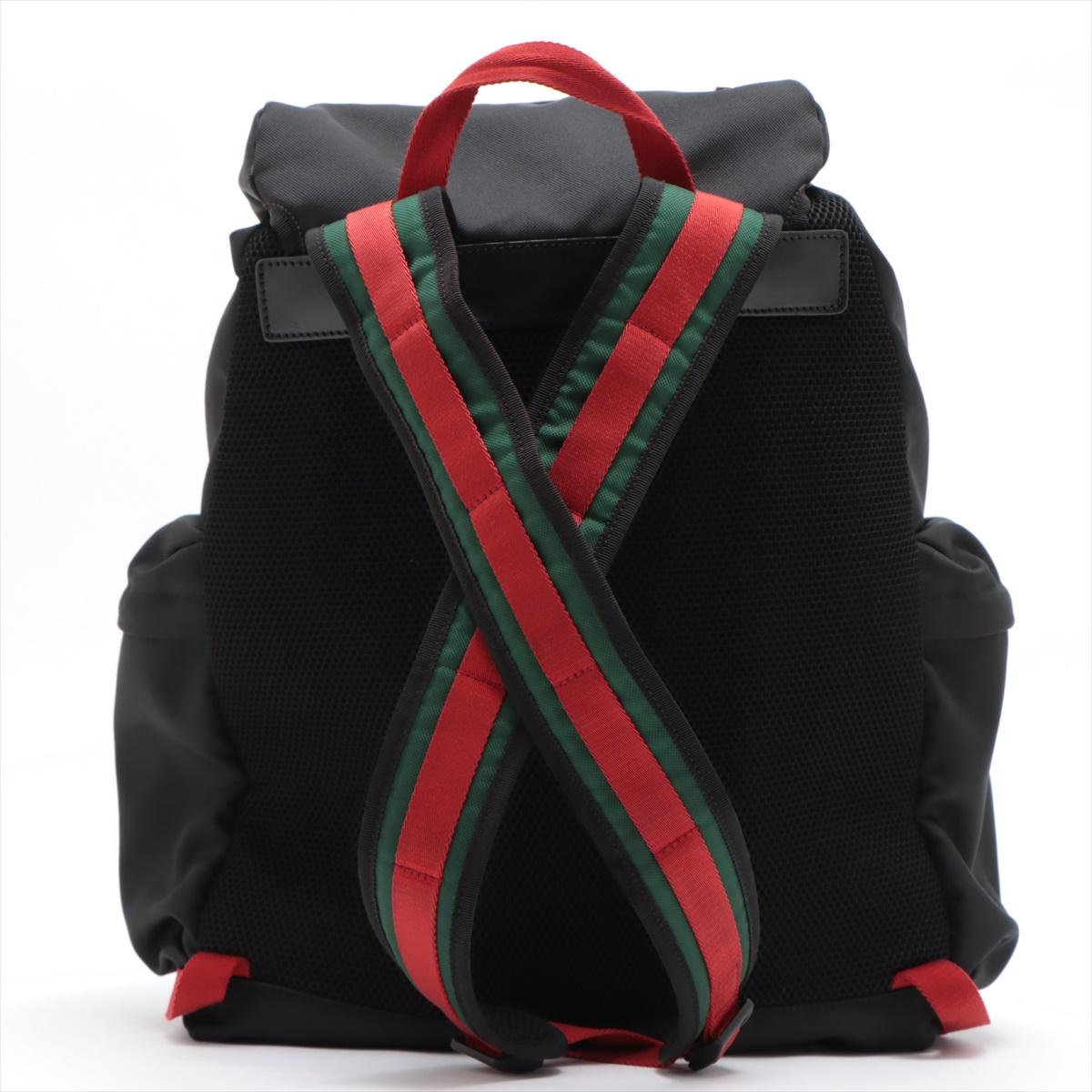 Black nylon Gucci Tiger Head backpack with silver-tone hardware, dual exterior pockets with zip closure, red and navy blue Web accents at front, dual shoulder straps with green and red Web accents, single flat red canvas handle, flap at top with