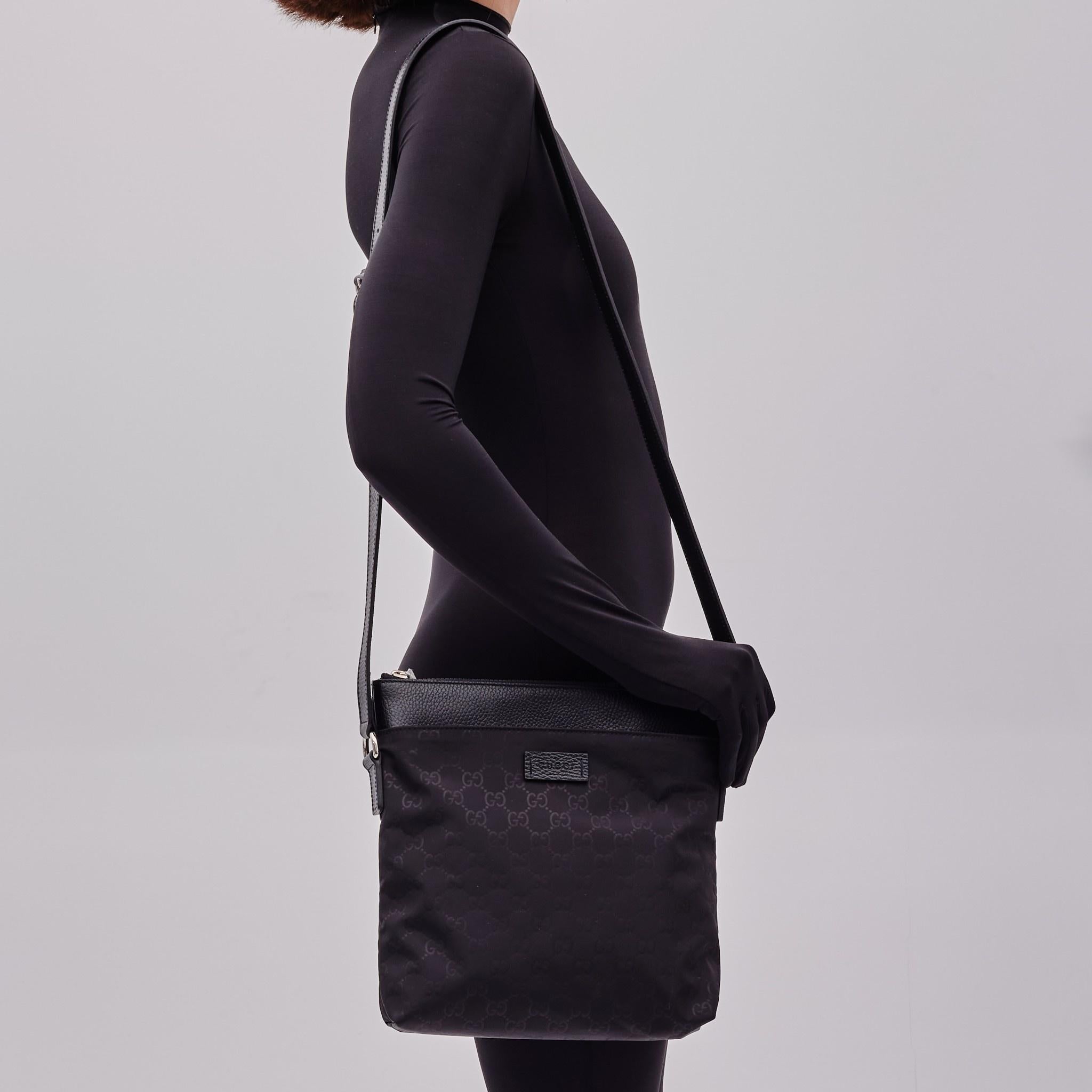 This messenger bag is made of monogram printed nylon in black. This bag features a large exterior pocket, an adjustable crossbody leather shoulder strap, and polished silver hardware. This opens to a black fabric interior with zipper and patch