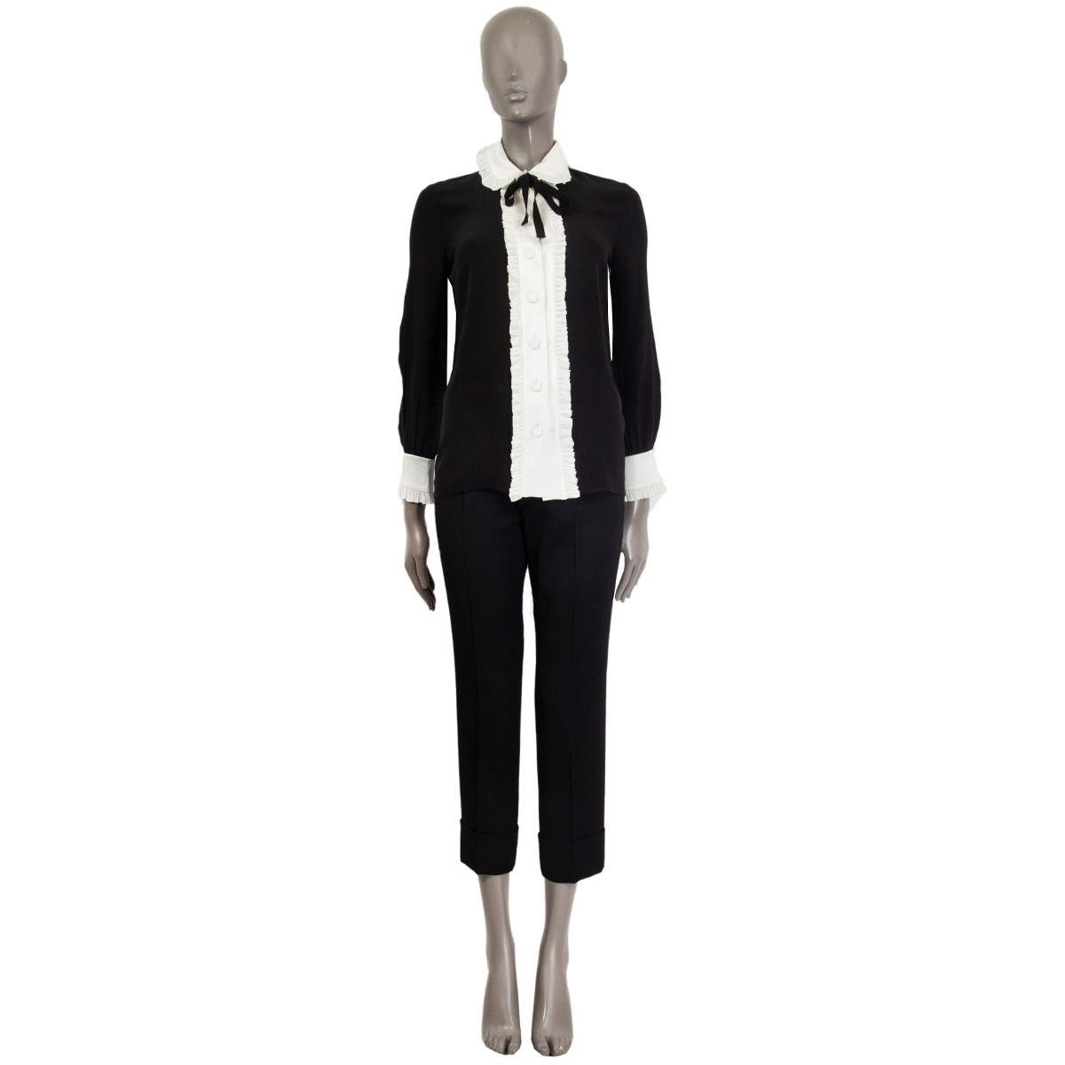 100% authentic Gucci ruffled blouse in black&white silk (missing content tag) with a black ribbon at the neck-line. Closes with eight buttons on the front and has ruffles on the collar-hem, along the front and on the cuffs-hem. Unlined. Has been