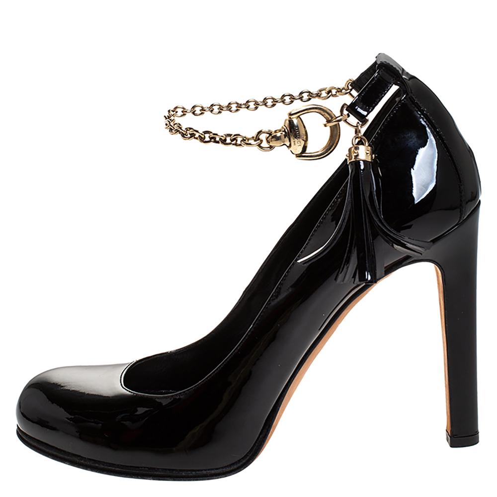 Gucci’s urban and gorgeous pumps are classy and sophisticated. Crafted in black patent leather, they feature impressive chain details along with buckle fastenings & tassels at the ankle strap and round toes. The pair is accented with gold-tone
