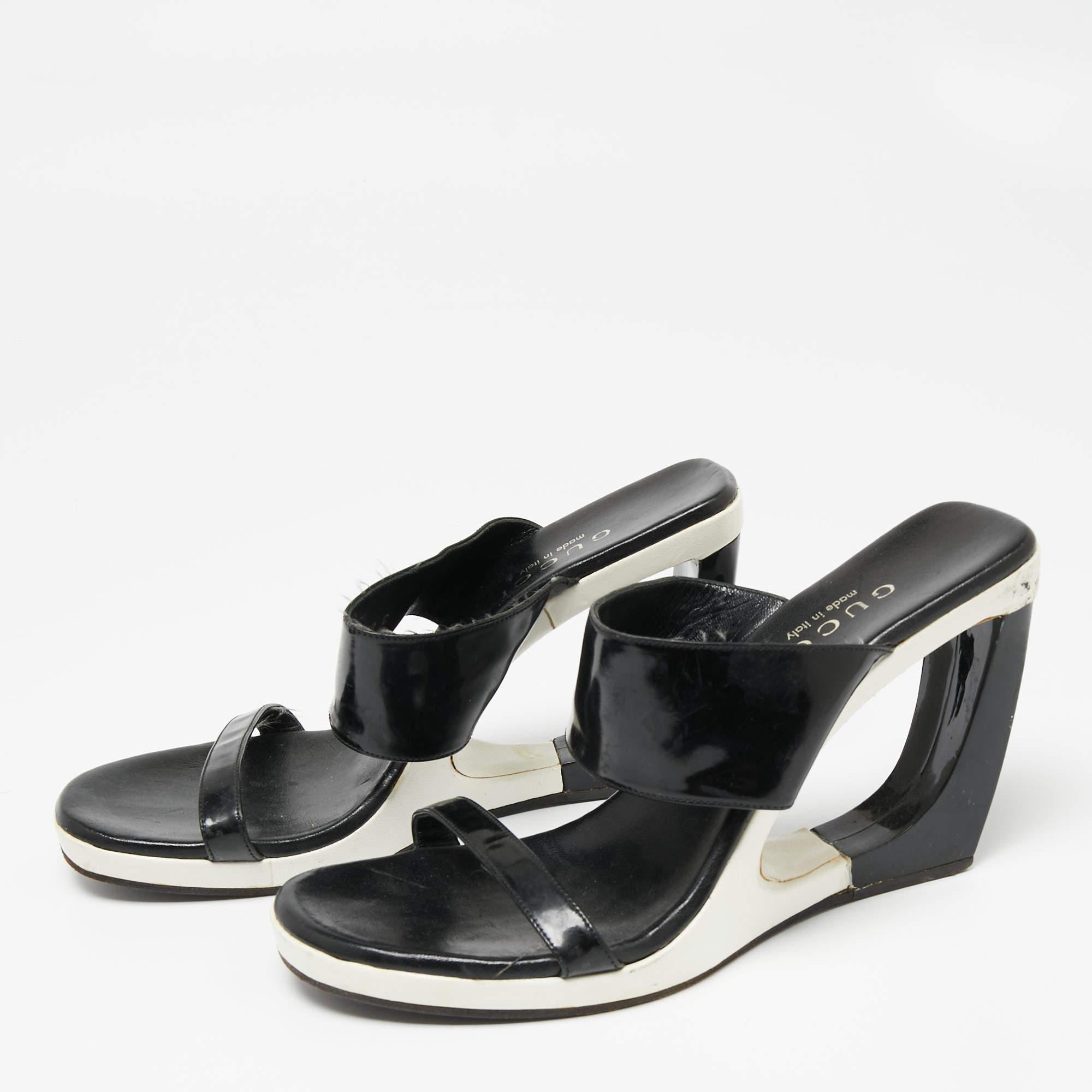 Updated with cut-out wedge heels, these Gucci sandals are the epitome of classic cool. Created from black patent leather, they are complemented with a slim and wide strap on the uppers. The open-toe silhouette is complete with a slip-on fitting and