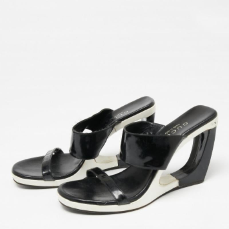 Updated with cut-out wedge heels, these Gucci sandals are the epitome of classic cool. Created from black patent leather, they are complemented with a slim and wide strap on the uppers. The open-toe silhouette is complete with a slip-on fitting and