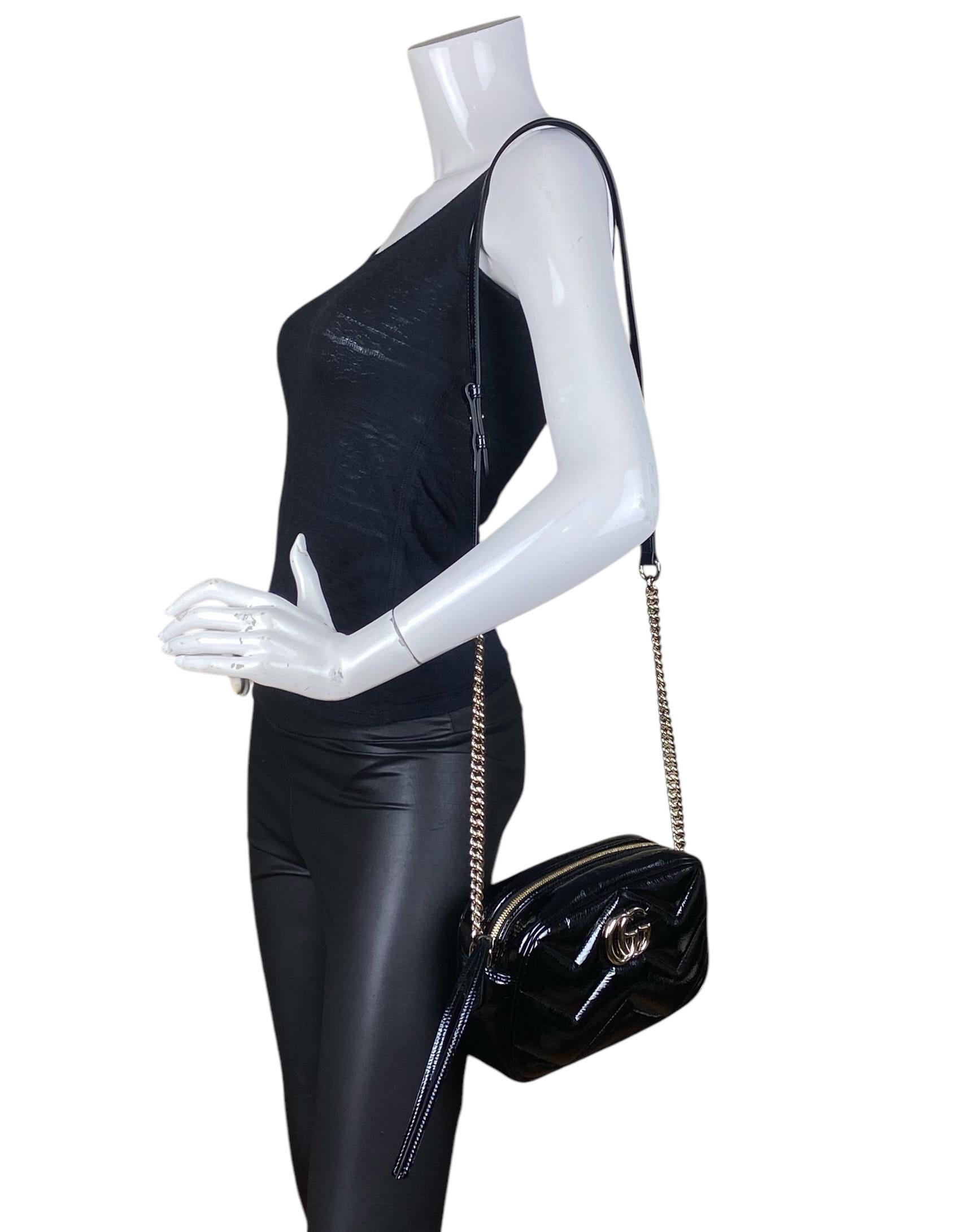 Sac à bandoulière Marmont en cuir verni noir de Gucci GG. Le petit sac pour appareil photo GG Marmont a une forme doucement structurée et une fermeture à glissière sur le dessus avec le matériel Double G. La bandoulière en chaîne est agrémentée d'un