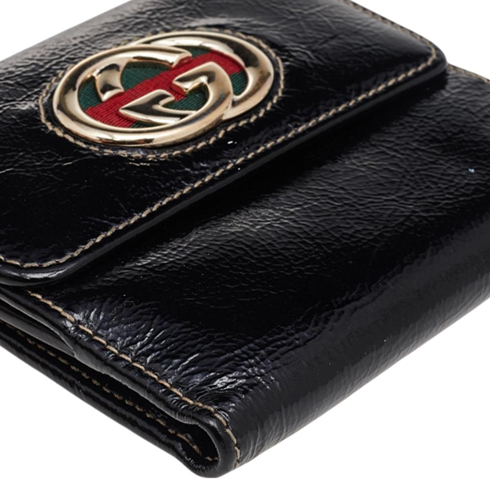 Keep your everyday belongings with style and ease in this compact wallet from the House of Gucci. It is made from black patent leather, with a GG motif and Web Britt stripe embellishment perched on the front. It has gold-toned hardware and a
