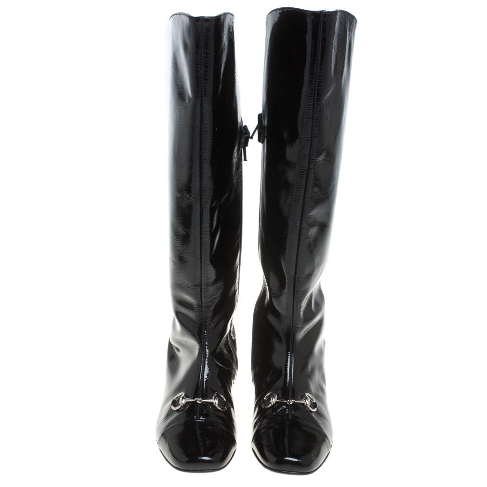 This bold yet chic pair of Gucci boots has a stylish silhouette and simple design. The knee-high boots have been crafted from black patent leather and feature Horsebit detail on the vamps. Representing the power dressing of modern women, these