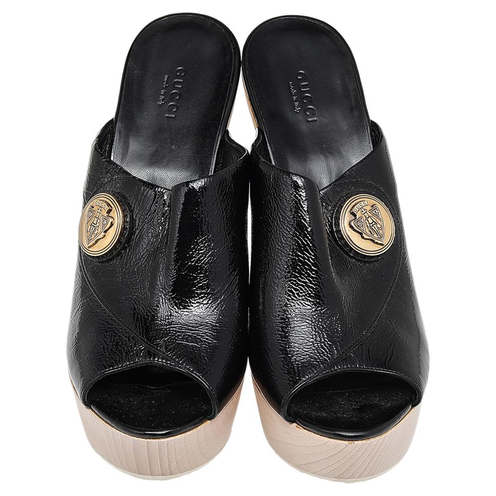 These Gucci clogs are comfortable and stylish. Crafted from glossy black patent leather, they feature gold-tone Gucci hardware, peep toe caps and wooden 15cm heels. These clogs are lined with leather Gucci labeled insoles.

Includes: Original Dustbag