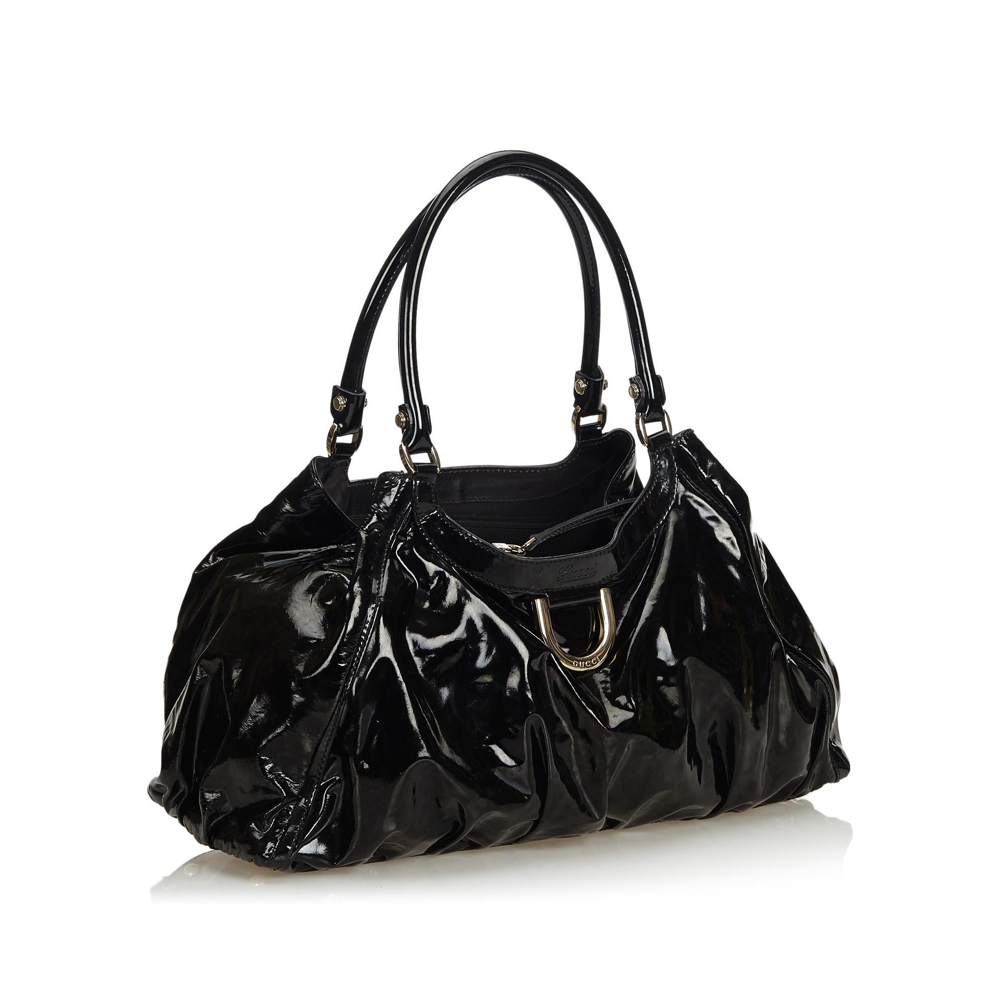 The Abbey D-Ring shoulder bag features a patent leather body with metal hardware, a rolled handle, a top zip closure, and an interior zip pocket. It carries as B+ condition rating.

Inclusions: 
This item does not come with