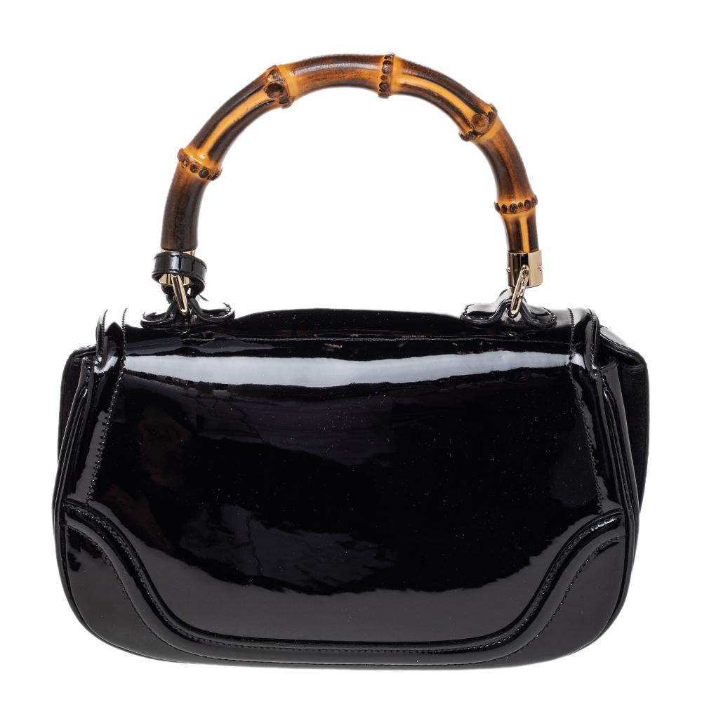 The New Bamboo bag is a Gucci gem that joins the brand's list of investment-worthy designer bags. Crafted in black patent leather, the bag has a flap design secured by a bamboo turnlock. It is lined with canvas and suede and held by a bamboo top