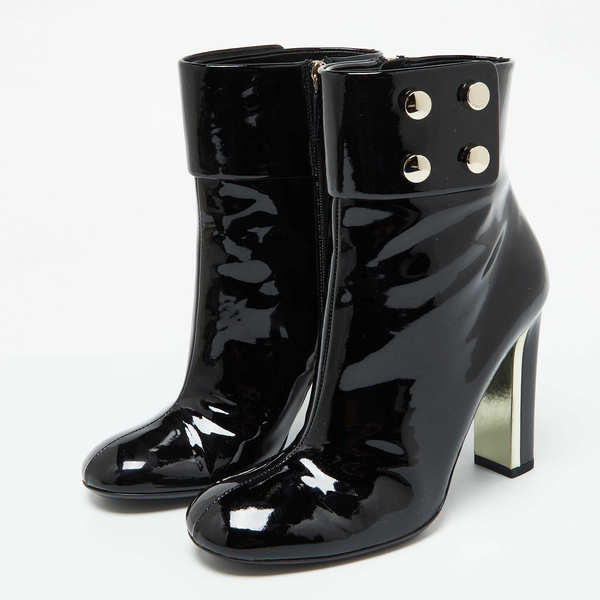 Con un diseño elegante y moderno  estos botines de Gucci realzarán tu look al instante. Están fabricados en charol negro y llevan tachuelas doradas en los laterales. Sobre tacones de bloque de 10 cm  estas botas se pueden peinar de múltiples maneras