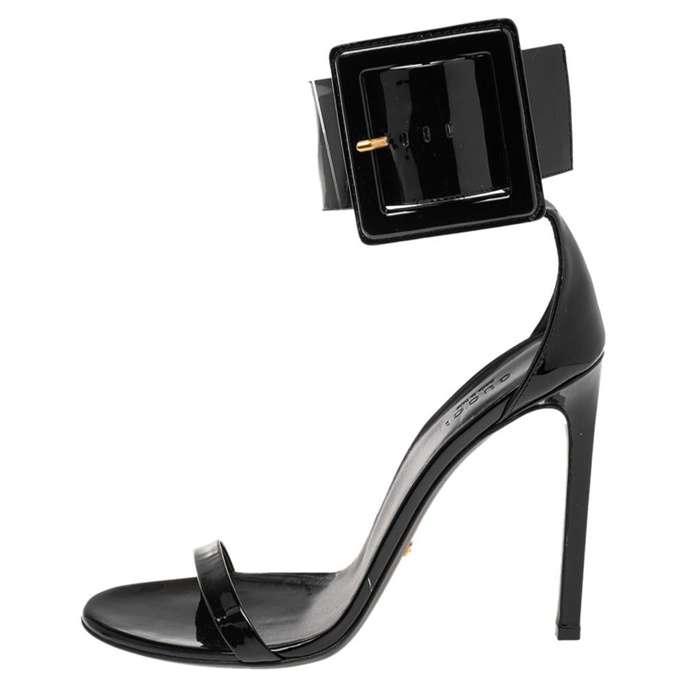 These black sandals from Gucci are made from patent leather into a gorgeous design. They feature a minimalist design of front straps, ankle cuffs, and 11.5 cm high heels to lift you every step of the way. The sandals can be worn with dresses or a