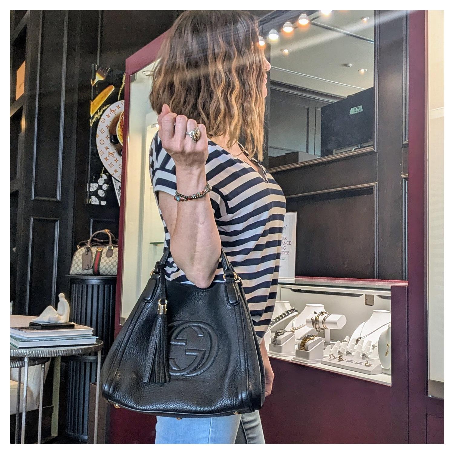 Indulge in luxury with the sophisticated Gucci Pebbled Calfskin Medium Soho Shoulder Bag. Crafted from pebbled calfskin, this designer handbag features an open top with clasp closure and a spacious interior lined with canvas. Complete with a stylish