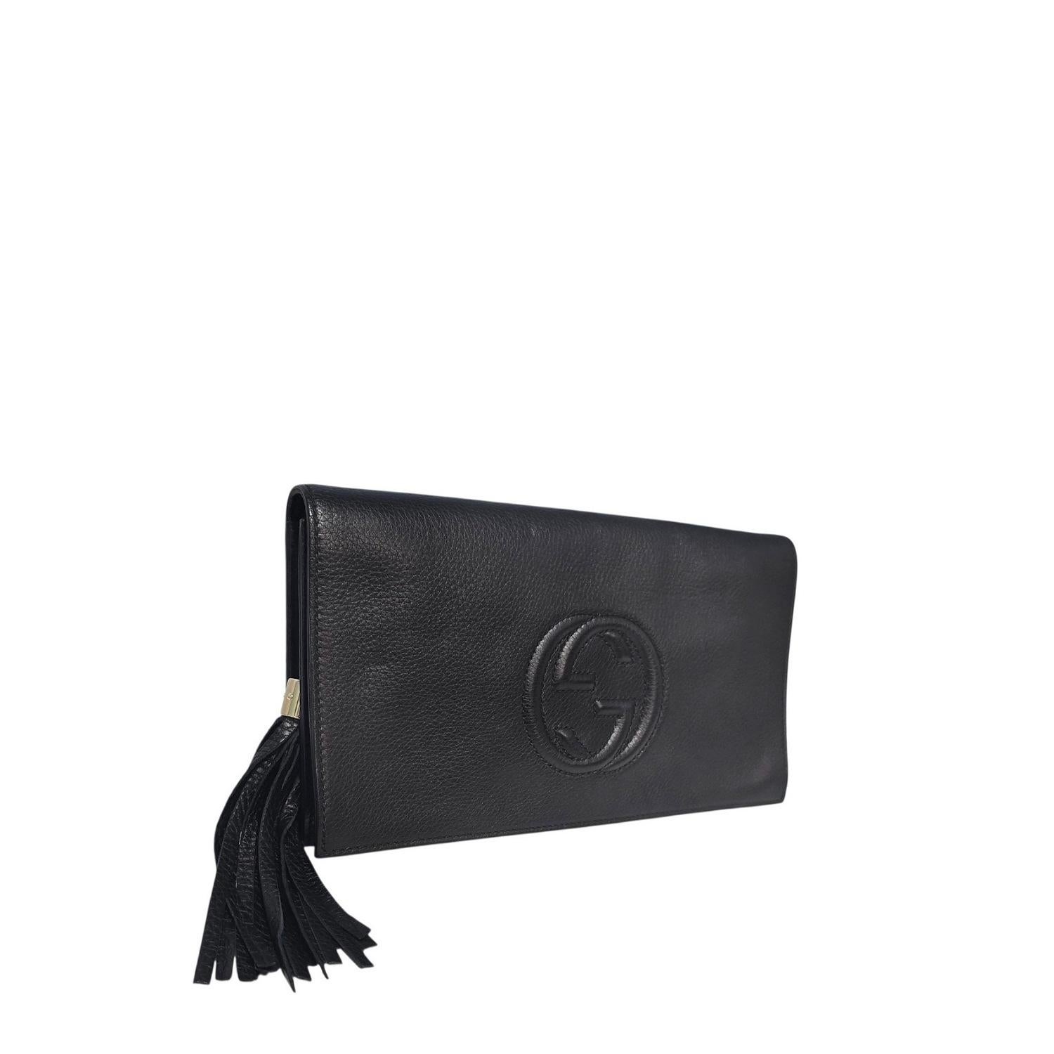 Scopri il lusso senza tempo con la Soho Clutch di Gucci in pelle di vitello nera. Caratterizzata da finiture dorate, chiusura a scatto magnetica e pratiche tasche interne, è progettata per un'eleganza versatile e quotidiana. Completo di nappina e