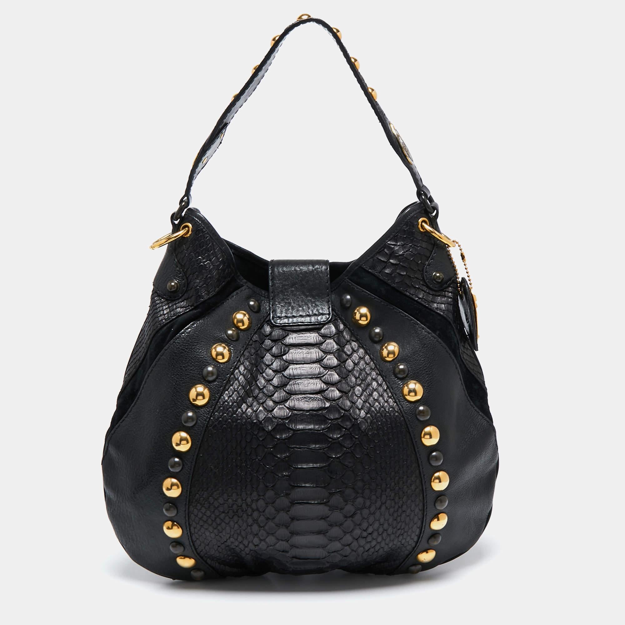 The Gucci Babouska hobo is a modern everyday bag with a chic Bohemian finish. This black bag is made of leather and python and is adorned with fringe detailing. It is finished with studs, a top handle, and a detachable shoulder strap. The spacious