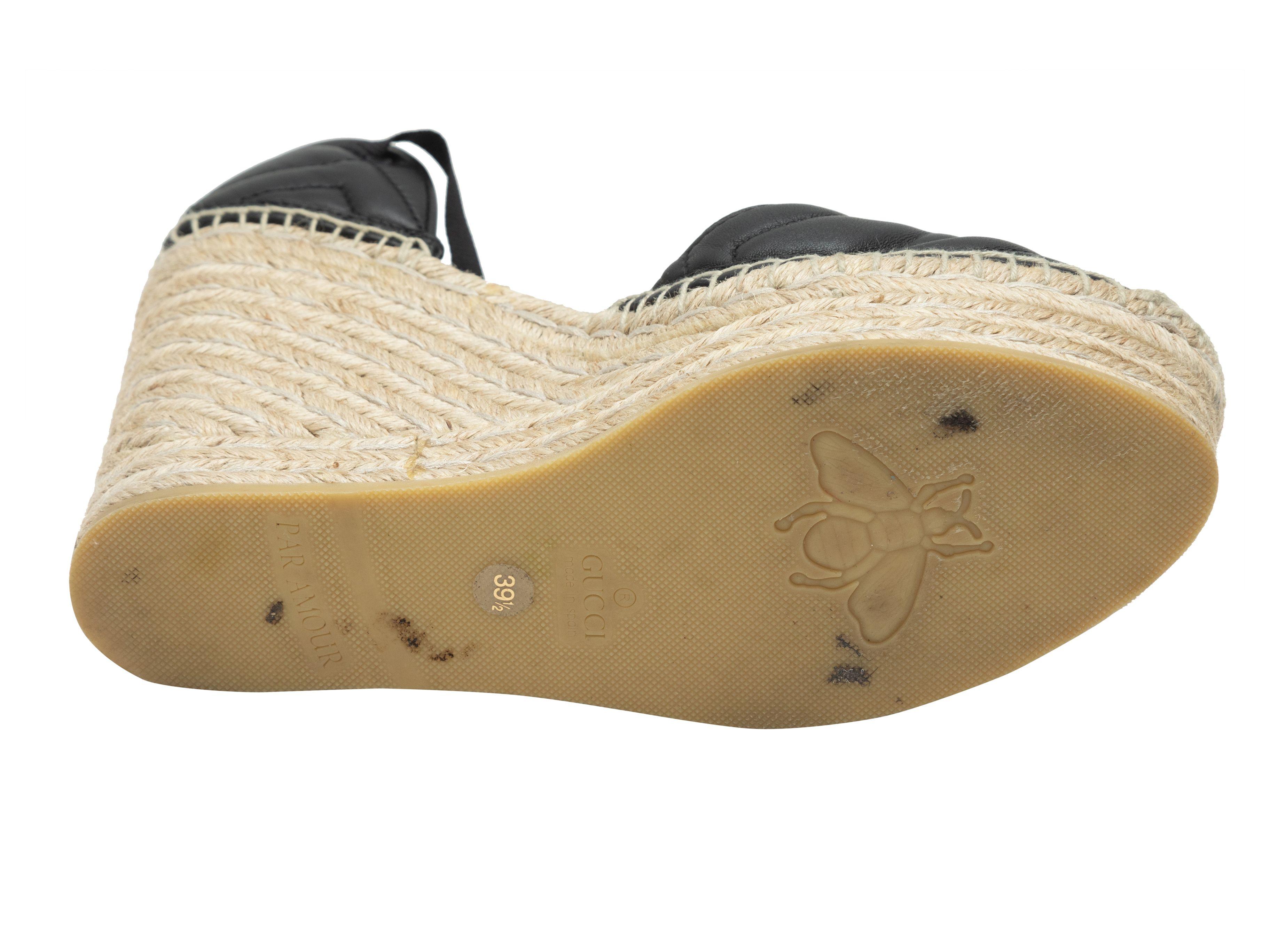 Détails du produit : Talons compensés en espadrille en cuir matelassé noir par Gucci. Médaillons GG en métal doré sur le dessus. Bordure en jute à la semelle. Fermeture à lacets en gros-grain au niveau des chevilles. Hauteur du talon de 4,75