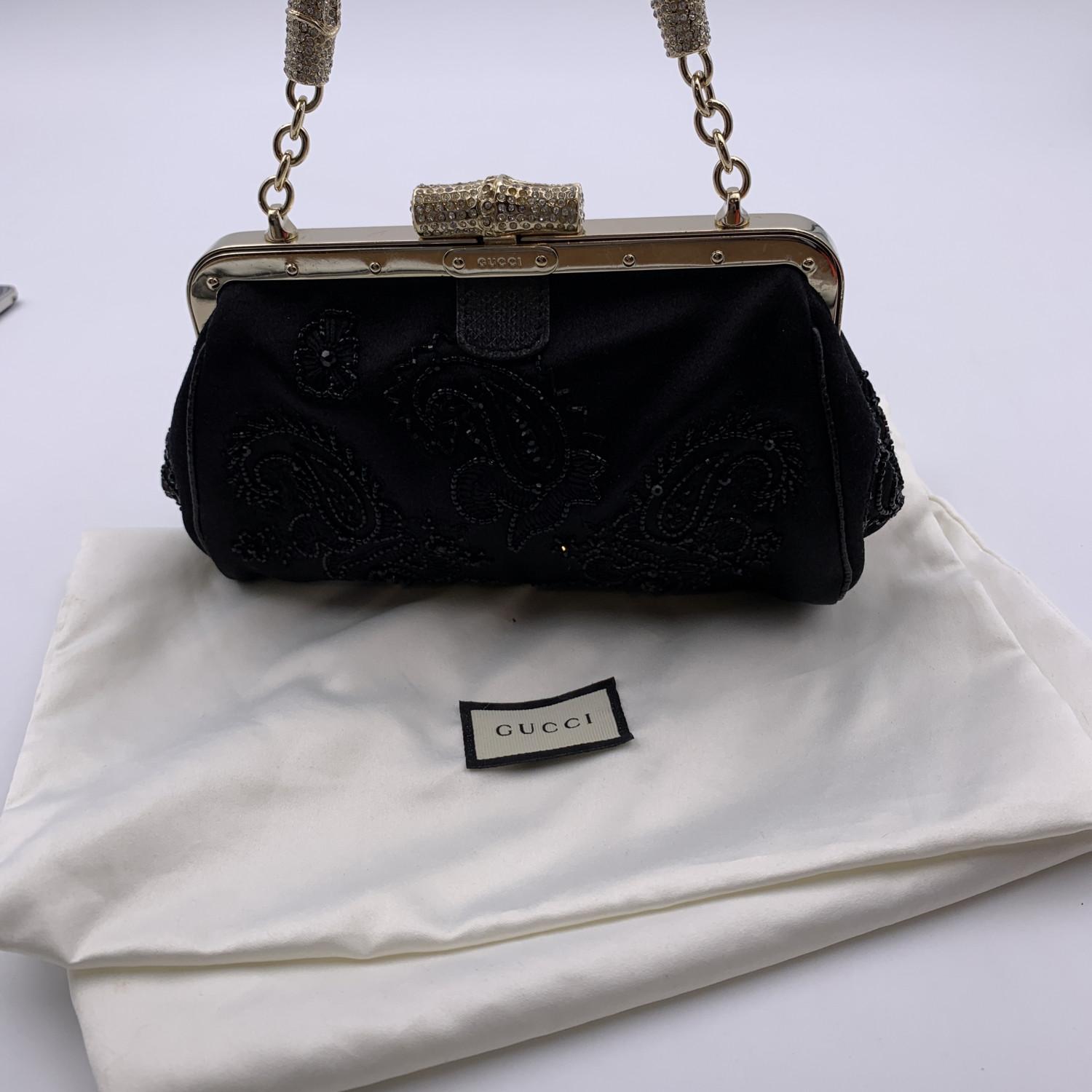 Gucci black embellished evening bag. Framed design. Gold metal hardware. Rhinestones detailing on the closure and on the handle.Black satin lining. 1 side open pocket inside. 'Gucci - Made in Italy' tag inside (with serial number on its