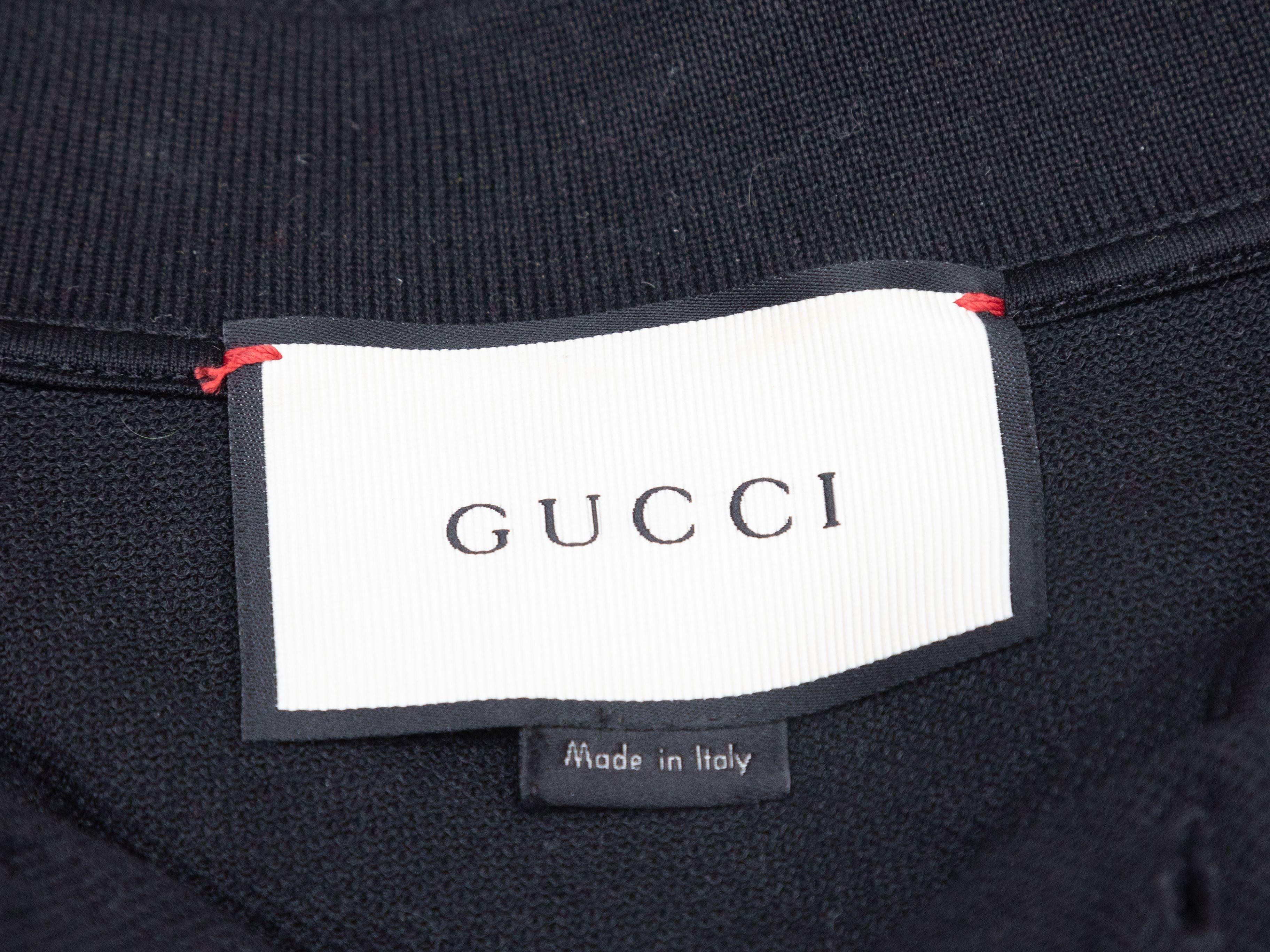 Product Details: Black short sleeve polo shirt by Gucci. Pointed collar. Logo patch at chest. Button closures at chest. 44