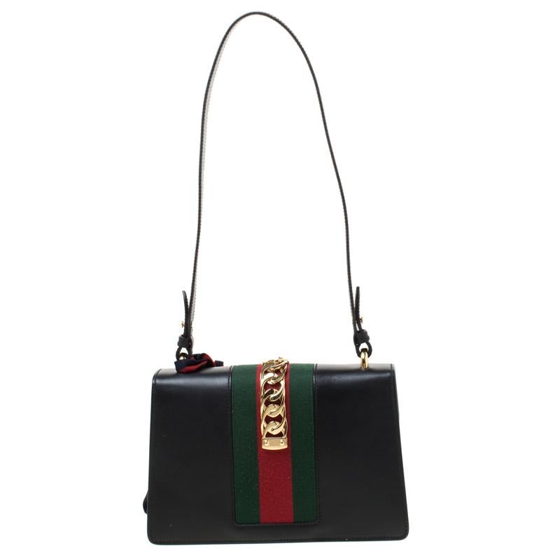 From the house of Gucci comes this gorgeous Sylvie shoulder bag that will perfectly complement all your outfits. It has been luxuriously crafted from black leather and styled with a chain-web decorated flap and a buckle lock to secure the suede