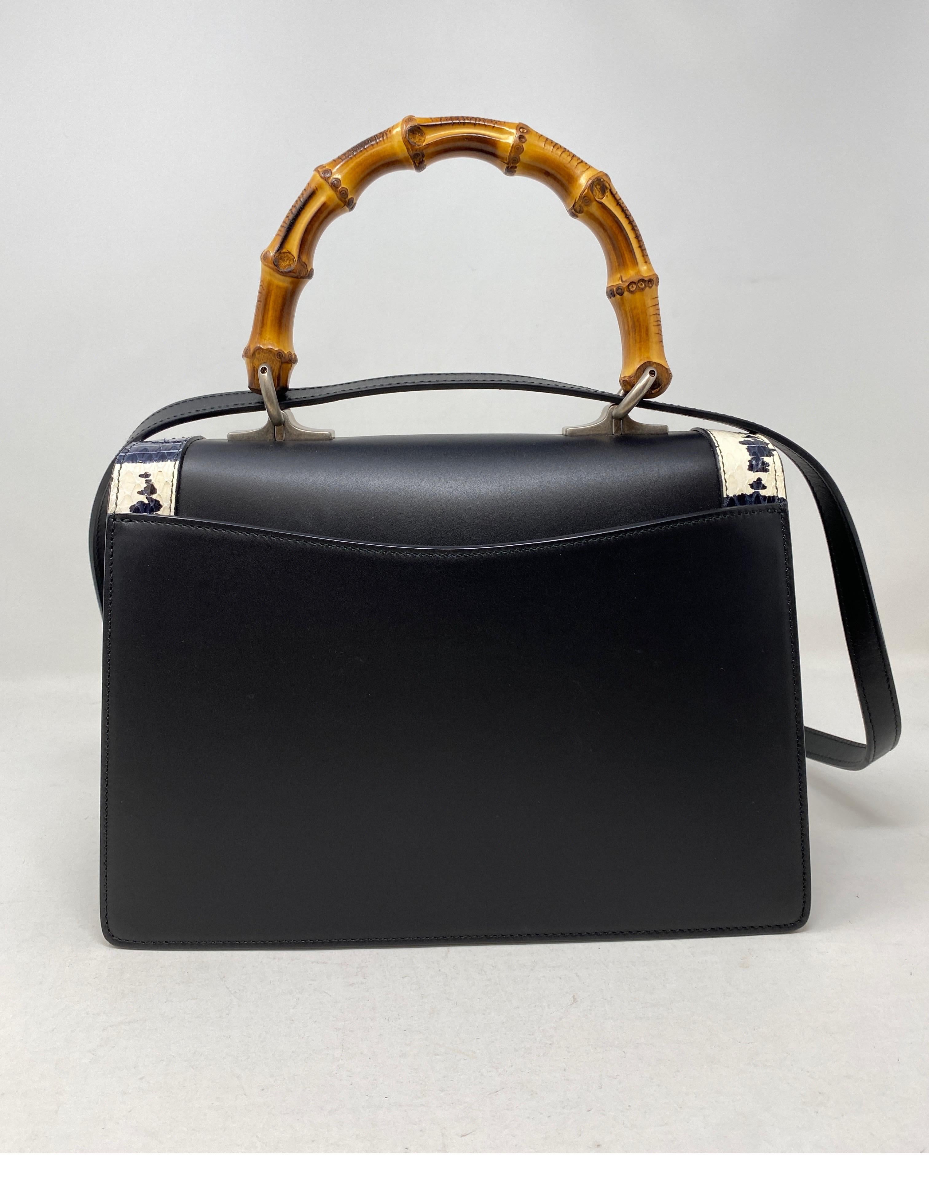 Black leather Gucci with wooden bamboo top handle. Also comes with removable adjustable leather strap and black ribbon bow strap. Metal snack head detail with stone detail and snake skin rim on flap. Silver varnished hardware detail. Excellent