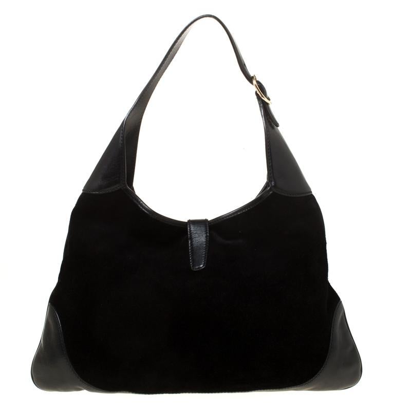 Get a modern yet classic look with this black suede Gucci Bouvier Jackie O hobo bag. The front features gorgeous gold-tone studs and ring designs down the middle, and a hook closure connected to a small leather flap. The bag also has a leather
