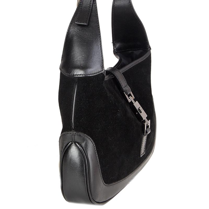 Le mini-sac à bandoulière 'Jackie O' de Gucci est en daim noir avec des garnitures en cuir noir. Il est doté d'une fermeture carrée en argent. Doublure en nylon noir avec une poche à fermeture éclair au dos. A été porté et est en excellent état.