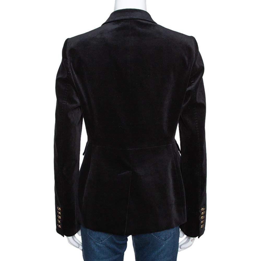Nothing gives you a better style than a well-tailored blazer. This creation by Gucci is cut from a black cotton blend exuding a velvet finish. The blazer features a notched collar and two-buttoned front closure and gold-tone horsebit detail on one