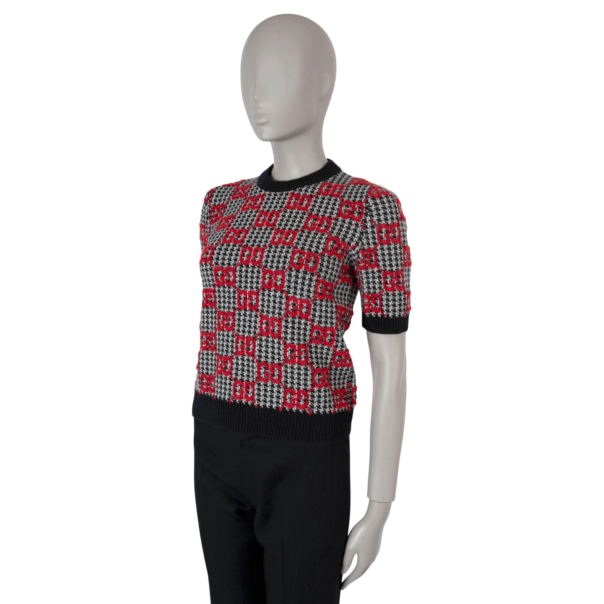 This 100% authentic Gucci sweater is crafted from black and white houndstooth knit wool (100%) with a striking red GG-jacquard pattern. It features a crew neck, short sleeves, and black rib-knit trims for a refined finish. This sweater pairs